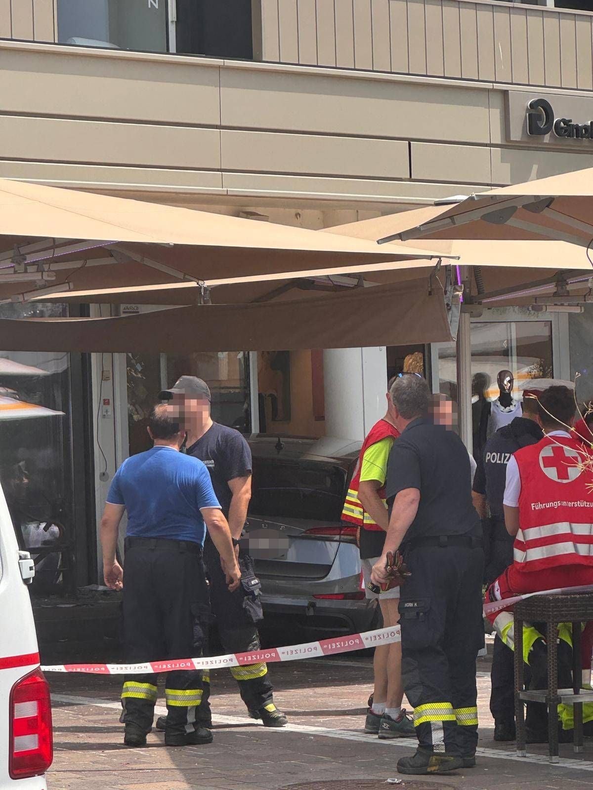 Polizei, Feuerwehr und Rettungsdienst stehen vor einem Auto, das in ein Café in Velden gefahren ist.