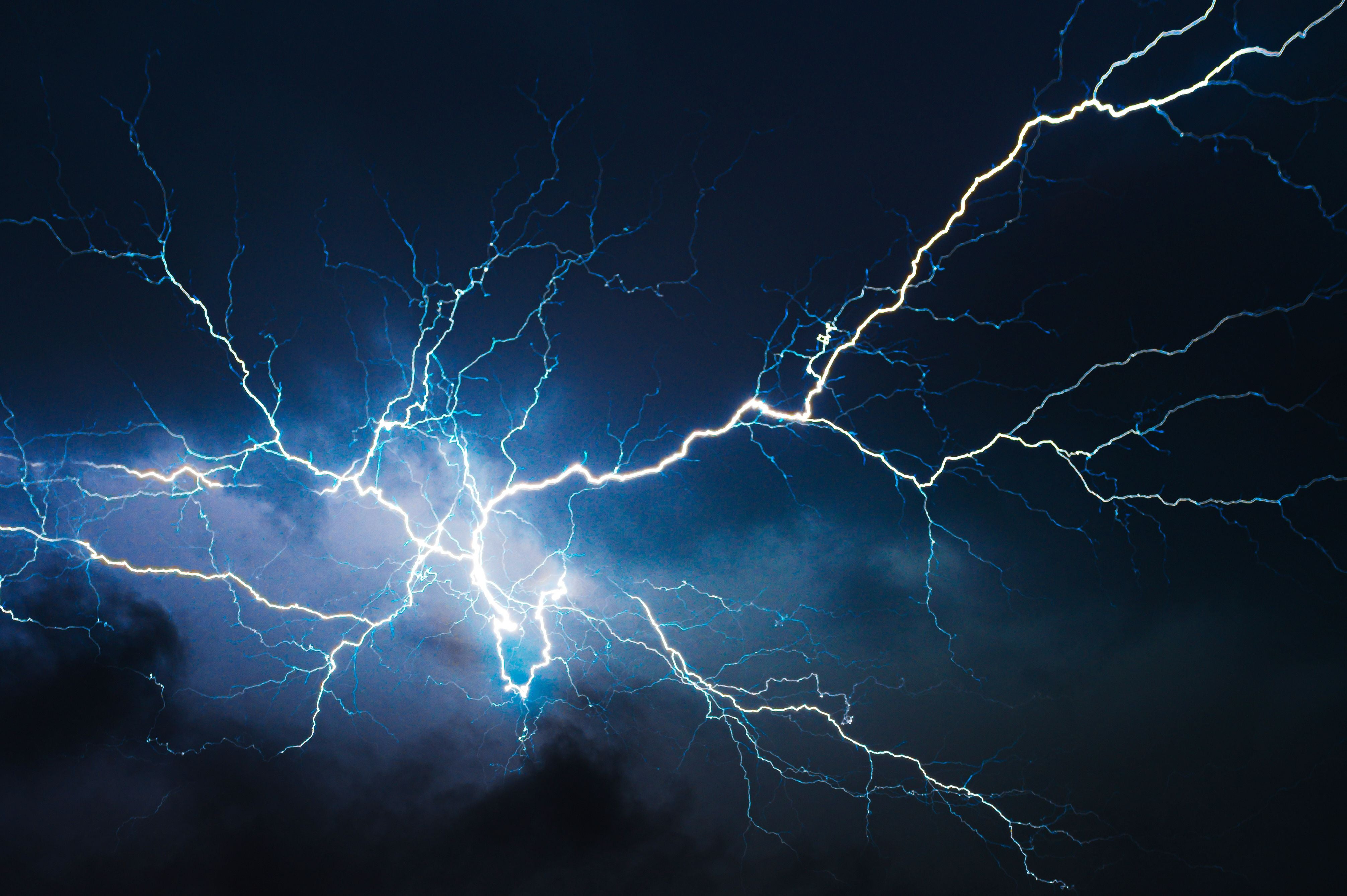 Helle Blitze durchzucken dunkle Nachtwolken und erleuchten den Himmel dramatisch.