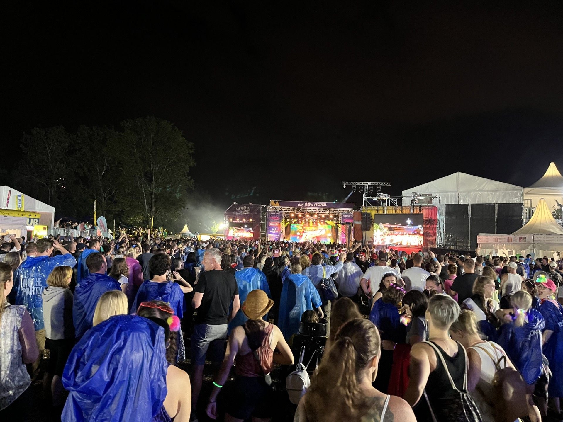 Große Menschenmenge bei einem Open-Air-Konzert mit beleuchteter Bühne in der Nacht.