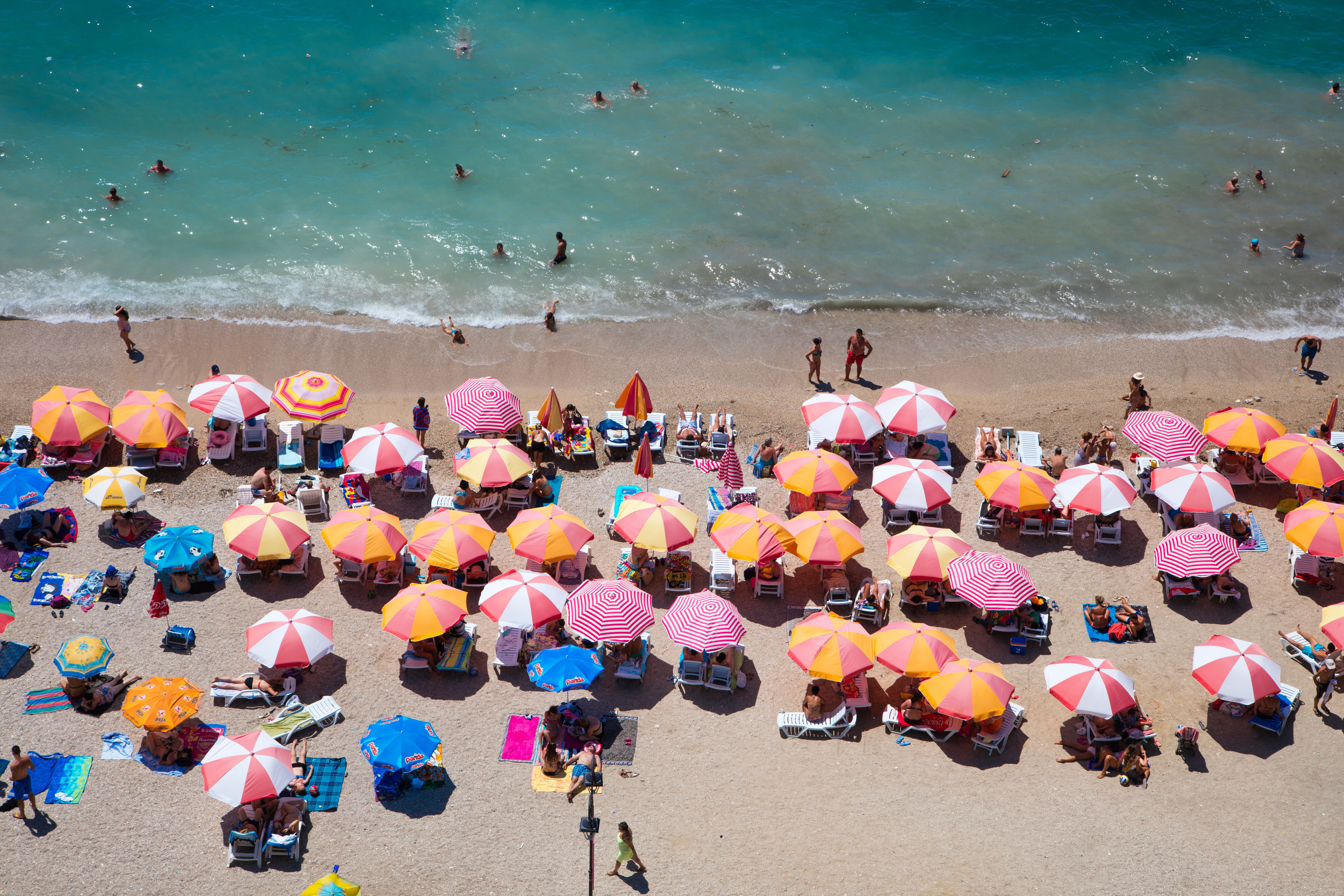 Viele bunte Sonnenschirme und Badende am belebten Strand von Saranda, Vlore, Albanien.