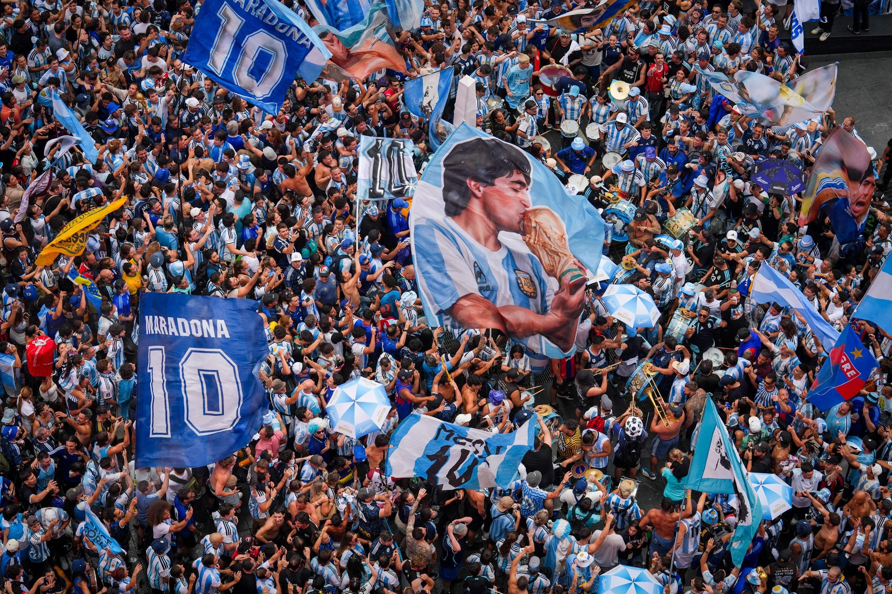 Argentinische Fans feiern mit Maradona-Fahnen und Trommeln bei einem großen Straßenfest.