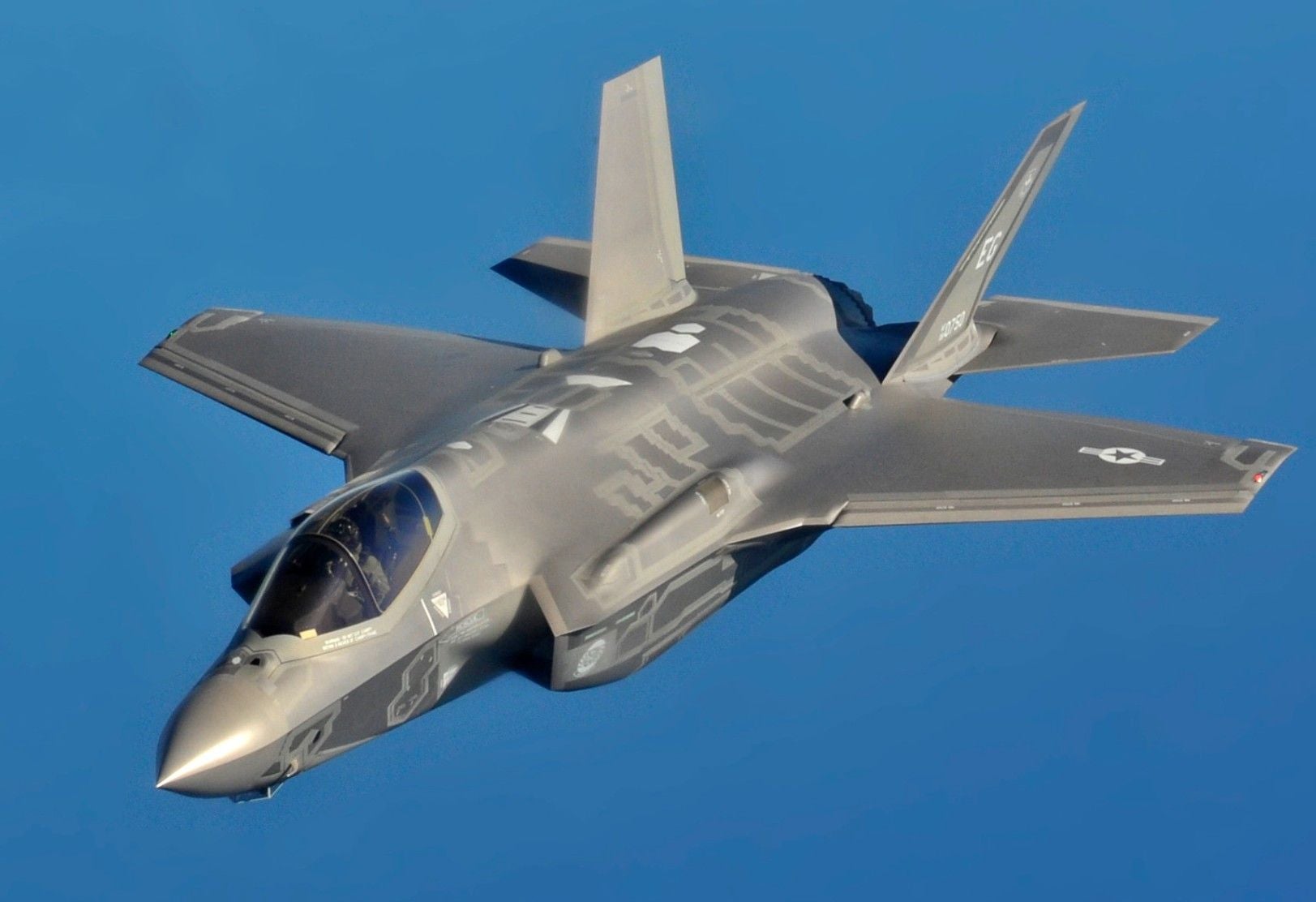 Ein graues F-35-Kampfflugzeug fliegt vor blauem Himmel.