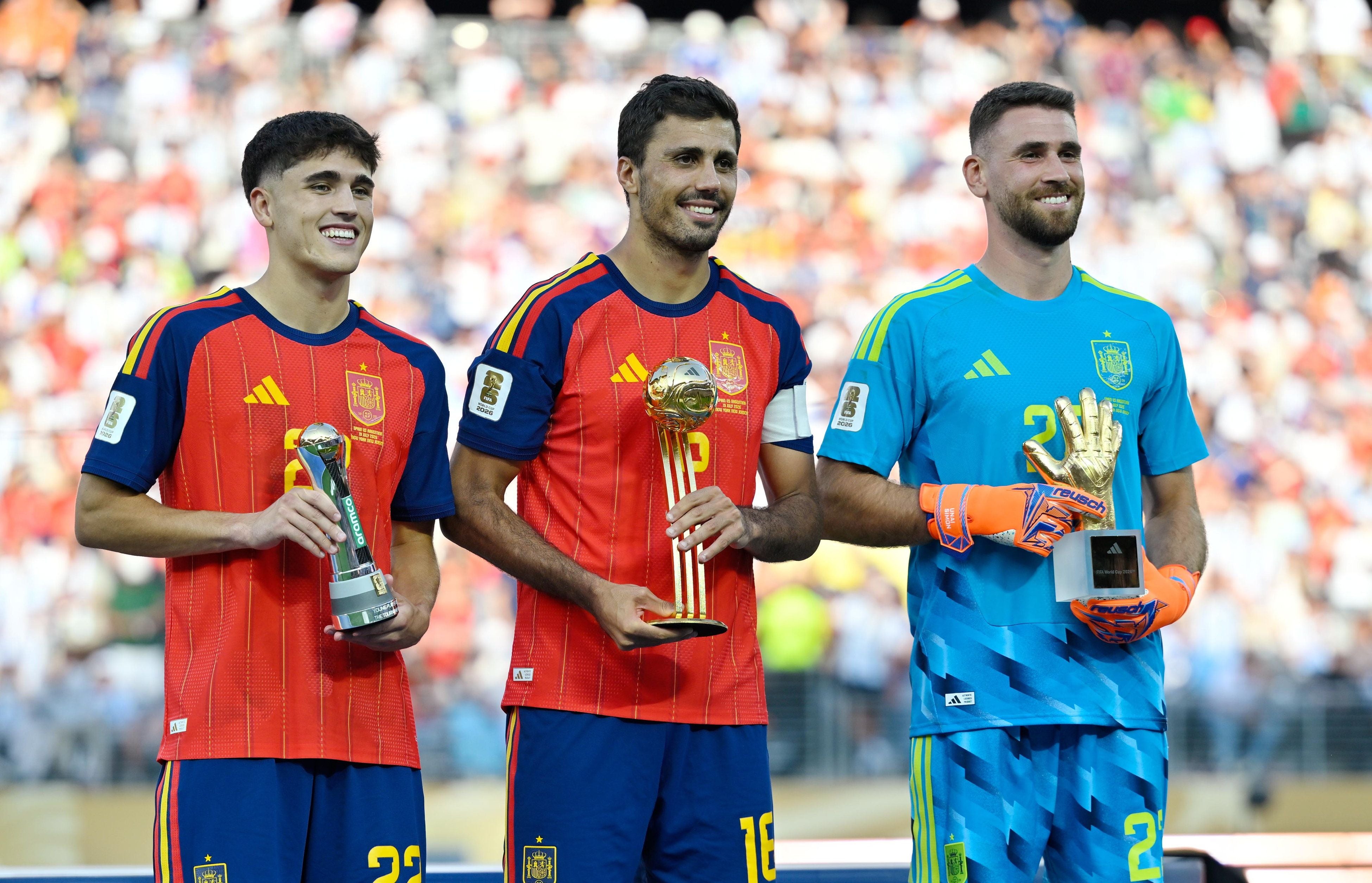 Drei spanische Fußballspieler posieren mit Turnierpokalen für beste Leistungen der WM 2026.