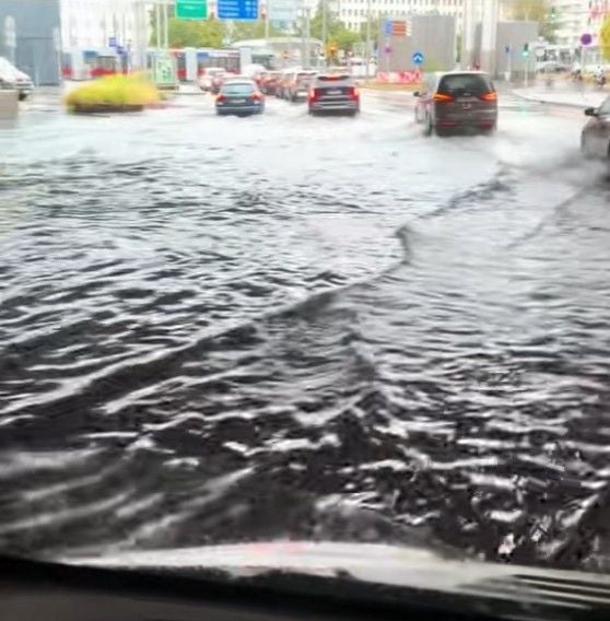 Straße am Praterstern in Wien ist nach starkem Regen überflutet, Autos fahren durch das Wasser.