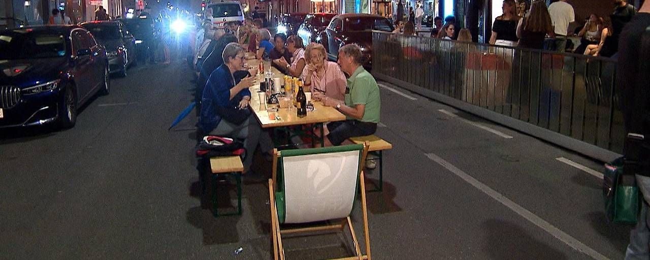 Aus Protest: Anrainer sitzen abends an einem langen Tisch mitten auf einer gesperrten Straße und essen gemeinsam.