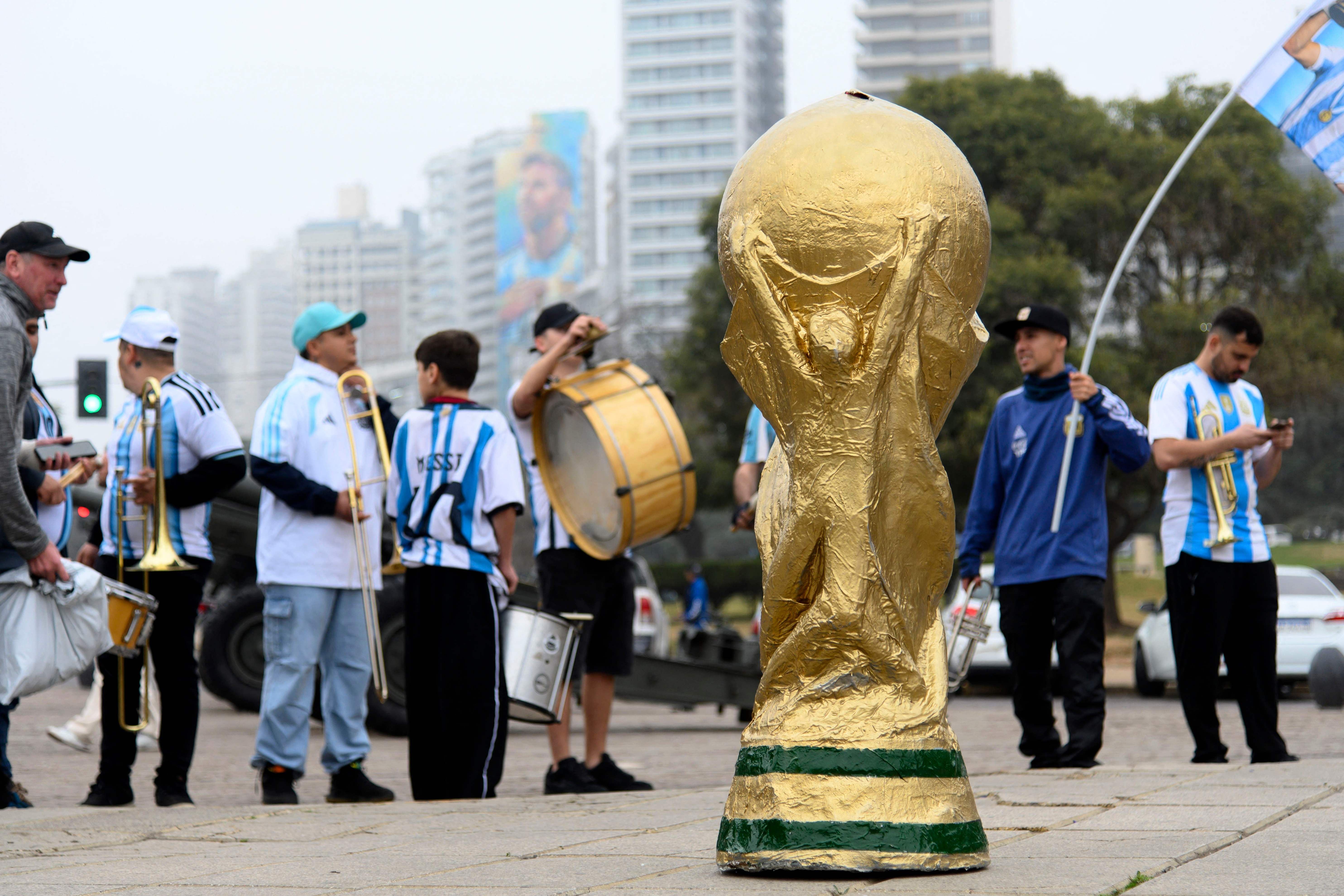 Nachbildung des WM-Pokals vor argentinischen Fans mit Trikots und Musikinstrumenten in Rosario.