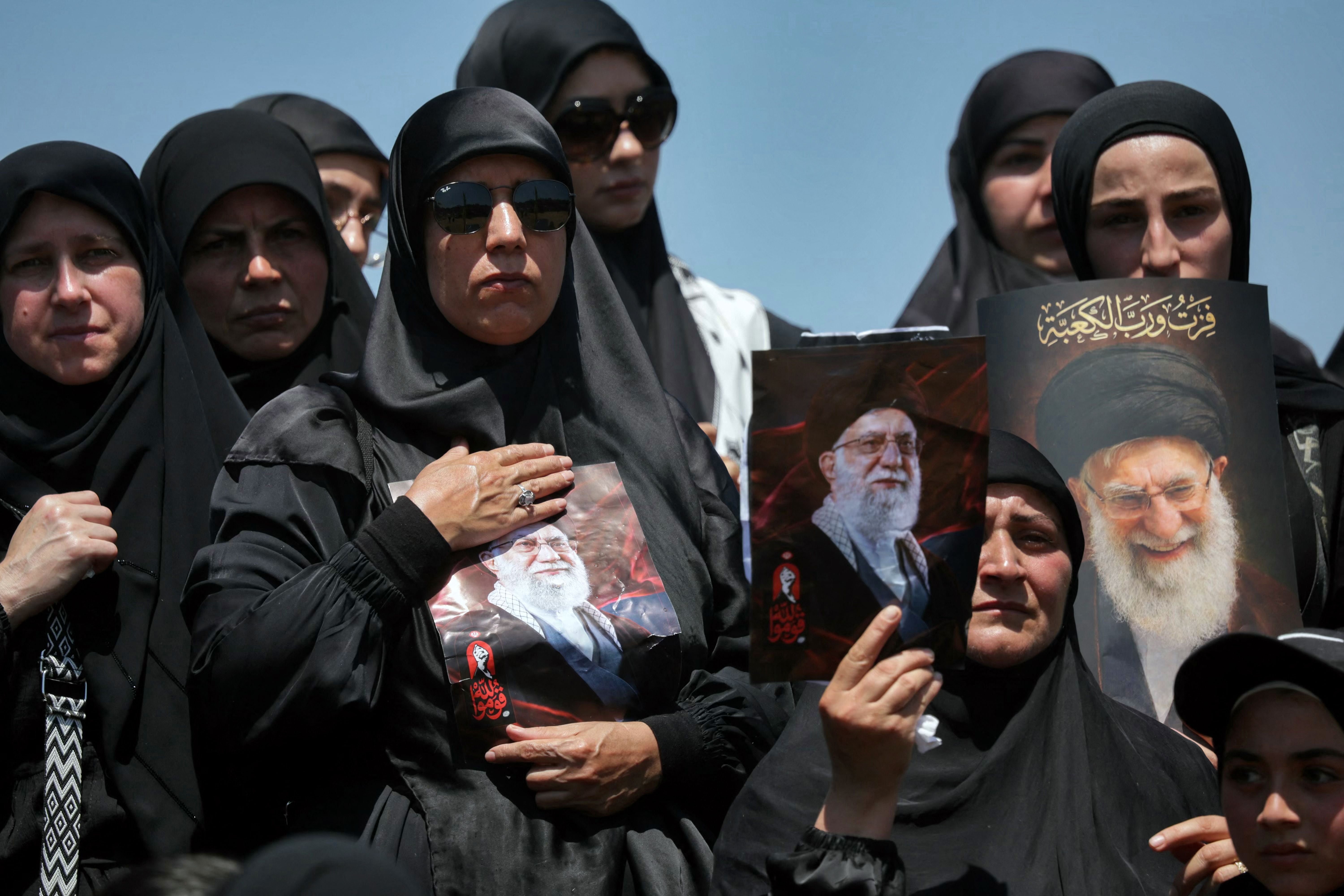Mehrere Frauen in schwarzer Kleidung halten Portraits von Ayatollah Ali Khamenei.