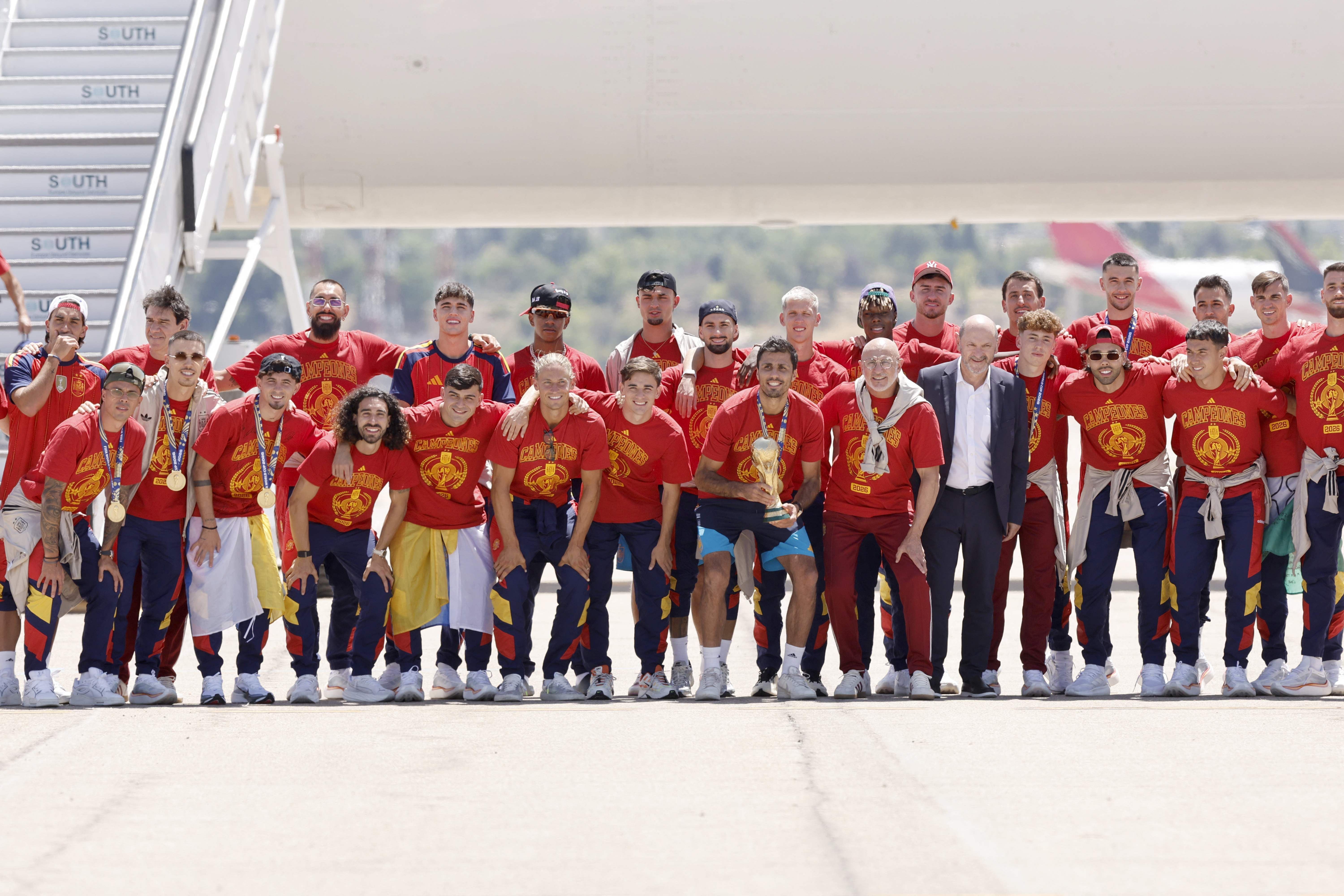 TOPSHOT - Spain's team pose with their trophy on the tarmac upon their arrival from the US after winning the 2026 World Cup, in Madrid Barajas' airport, on July 20, 2026. Spain's World Cup winners come back home to a heroes' welcome in Madrid, where a million fans are expected to greet them after a night of raucous celebrations across the country. (Photo by Oscar DEL POZO / AFP)
