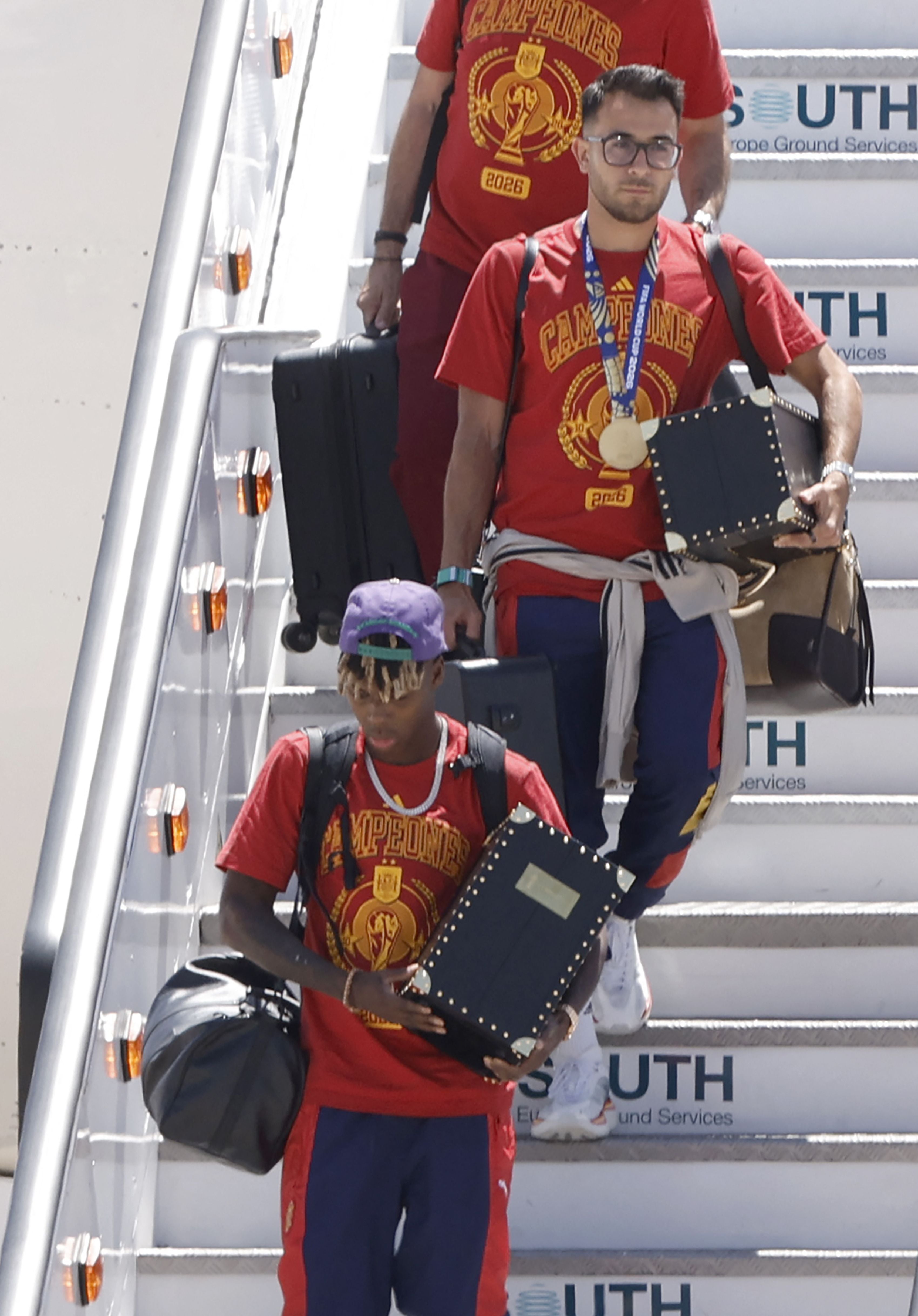 Spain's forward Lamine Yamal (BOTTOM) and Spain's defender #04 Eric Garcia disembark upon their arrival from the US after winning the 2026 World Cup, in Madrid Barajas' airport, on July 20, 2026. Spain's World Cup winners come back home to a heroes' welcome in Madrid, where a million fans are expected to greet them after a night of raucous celebrations across the country. (Photo by Oscar DEL POZO / AFP)