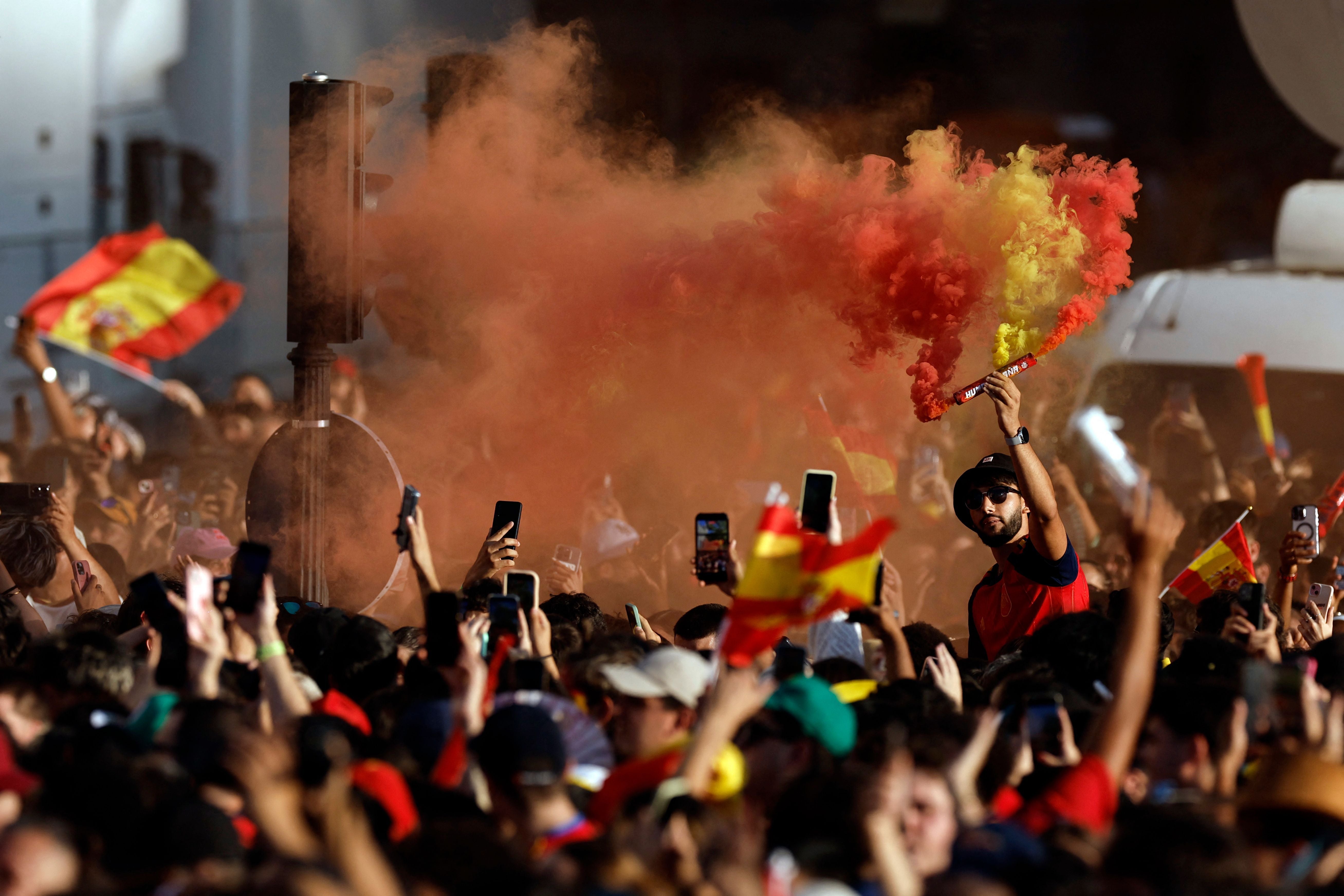 Menschenmenge in Madrid feiert mit rot-gelbem Rauch und spanischen Flaggen den WM-Sieg.