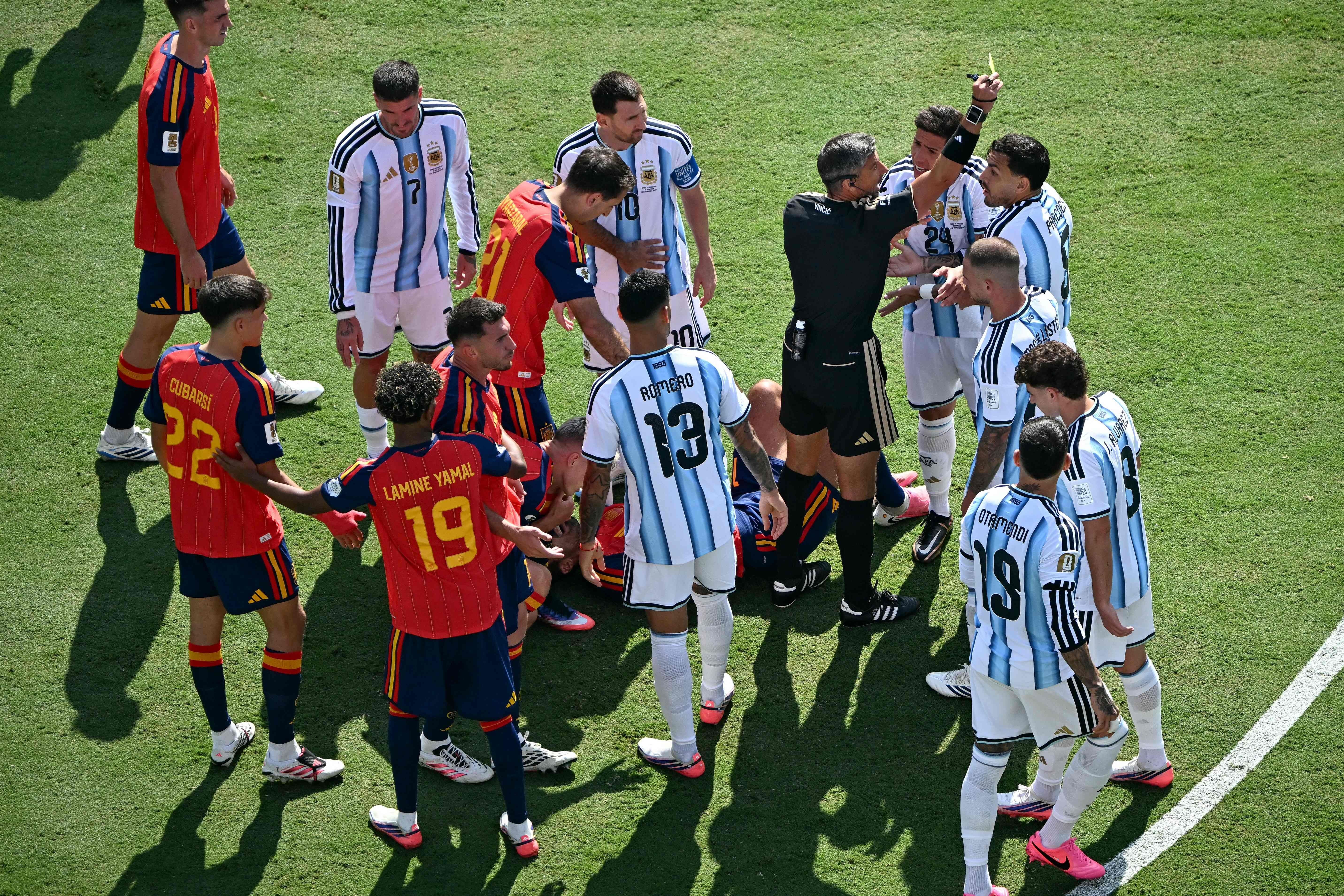 Schiedsrichter zeigt im Fußballspiel Spanien gegen Argentinien eine gelbe Karte, Spieler diskutieren.