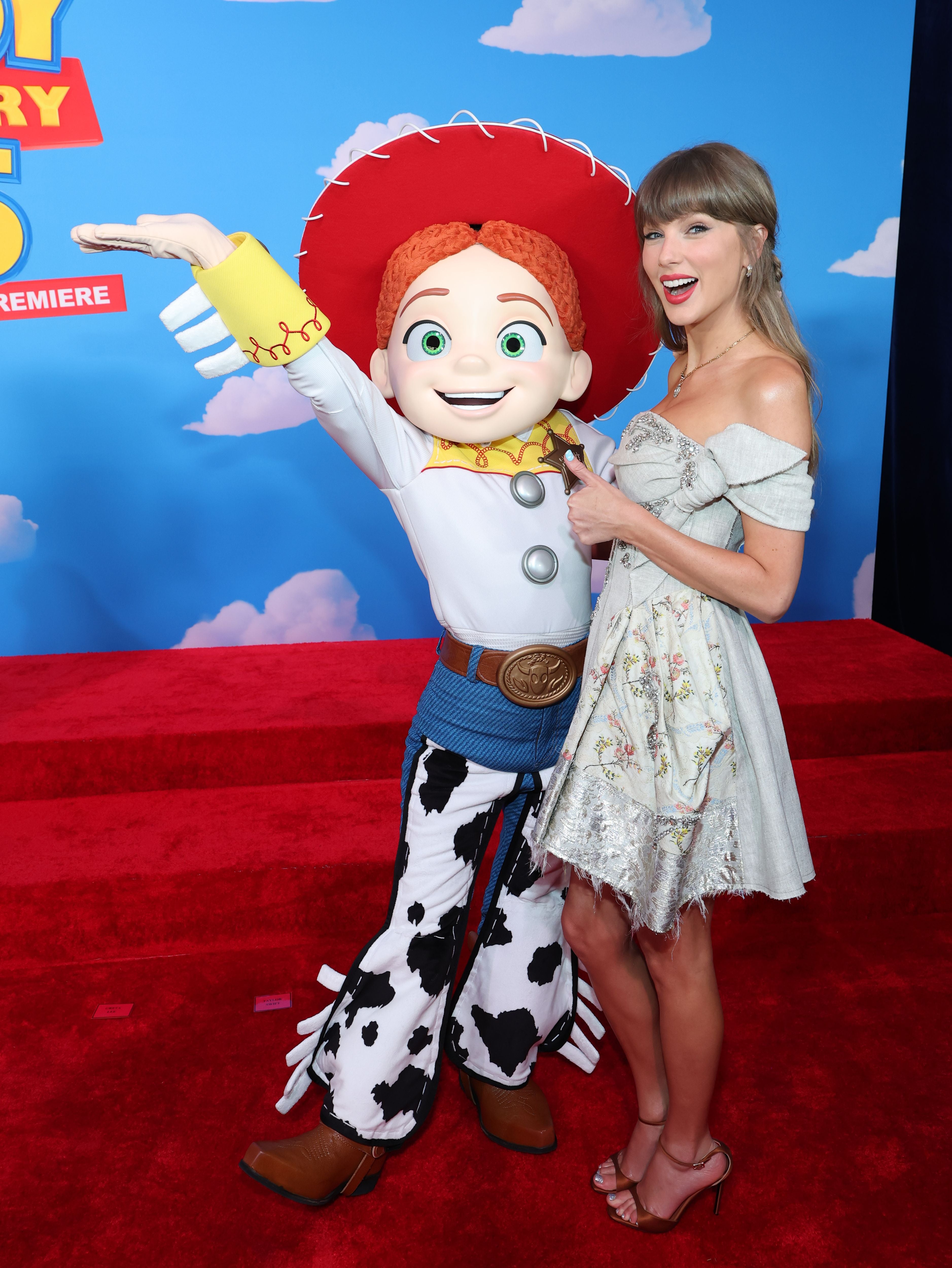 Taylor Swift posiert auf dem roten Teppich mit Jessie aus Toy Story bei einer Filmpremiere.