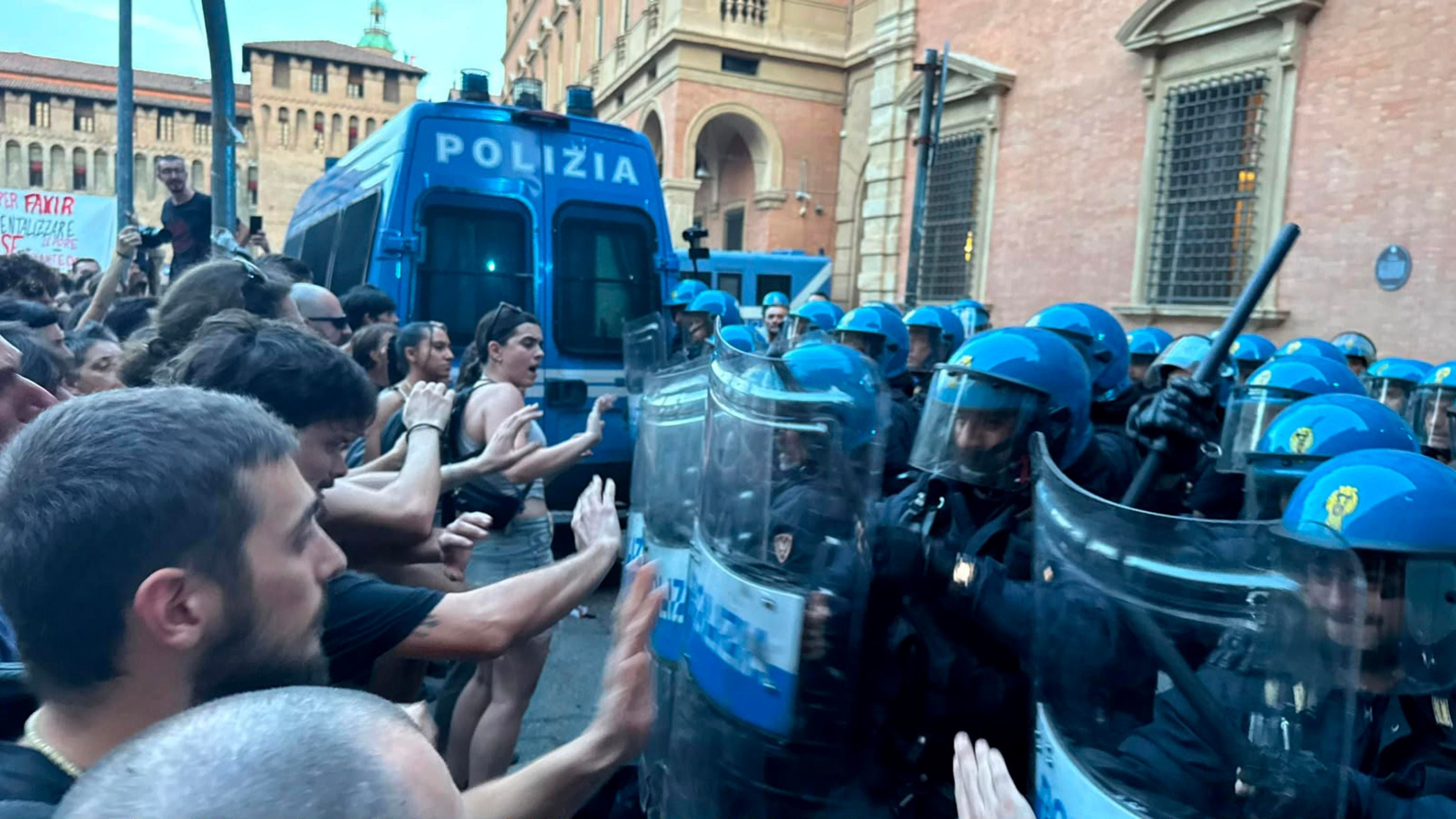 Demonstrierende stoßen bei Protesten in Bologna mit Polizisten in Schutzkleidung zusammen.