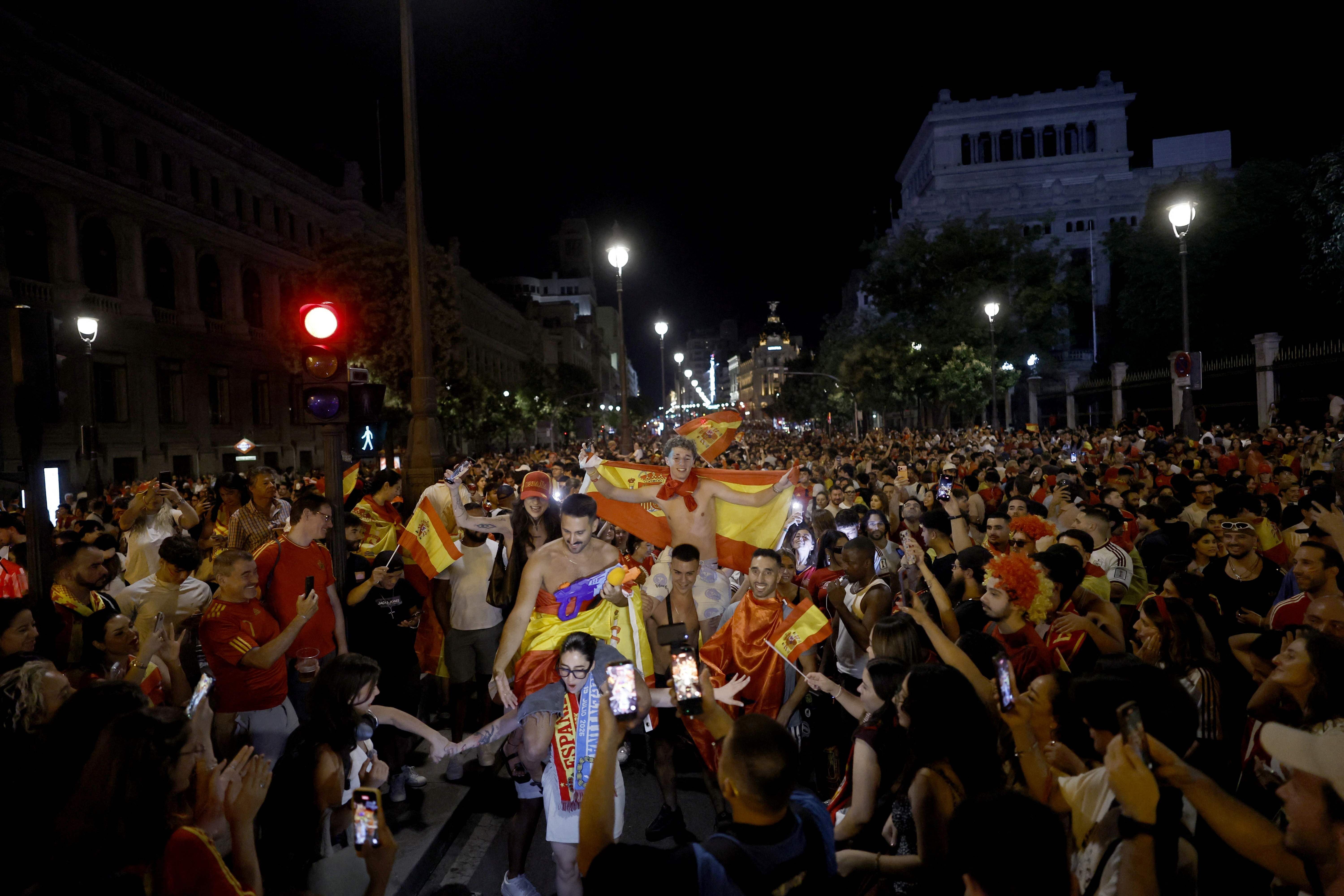 Menschenmenge in Madrid feiert Spaniens WM-Sieg bei Nacht mit Flaggen und Jubel auf der Straße.