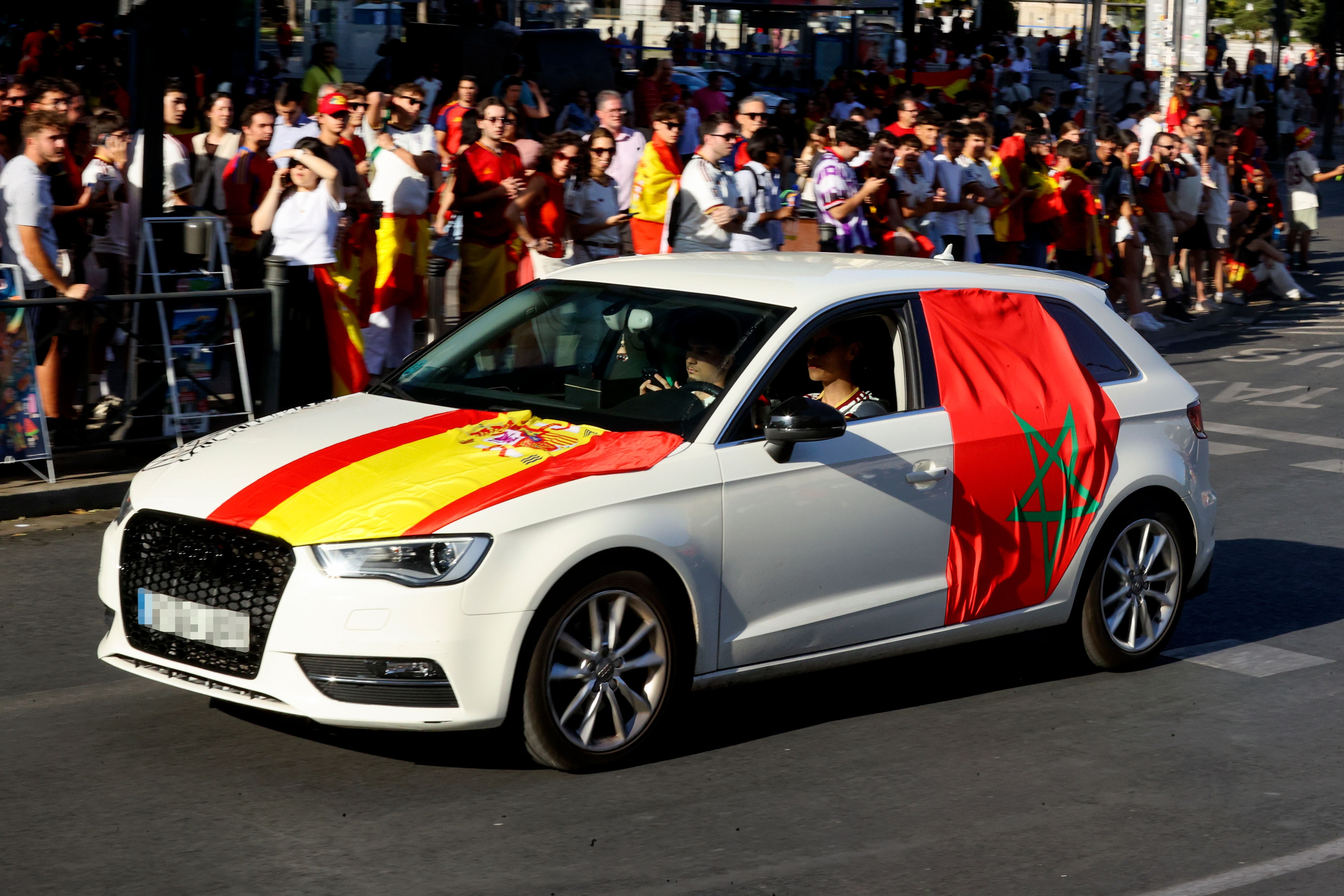 Auto mit spanischer und marokkanischer Flagge, viele Menschen feiern auf der Straße in Madrid.