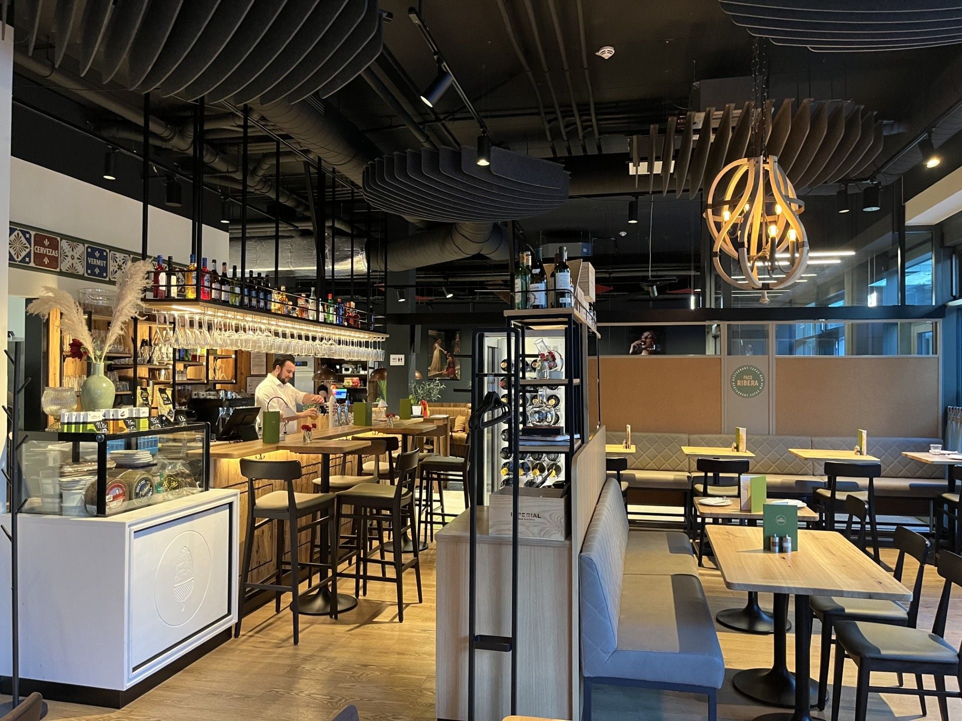 Modernes Restaurant mit Bar, Holzmöbeln und dekorativer Beleuchtung.