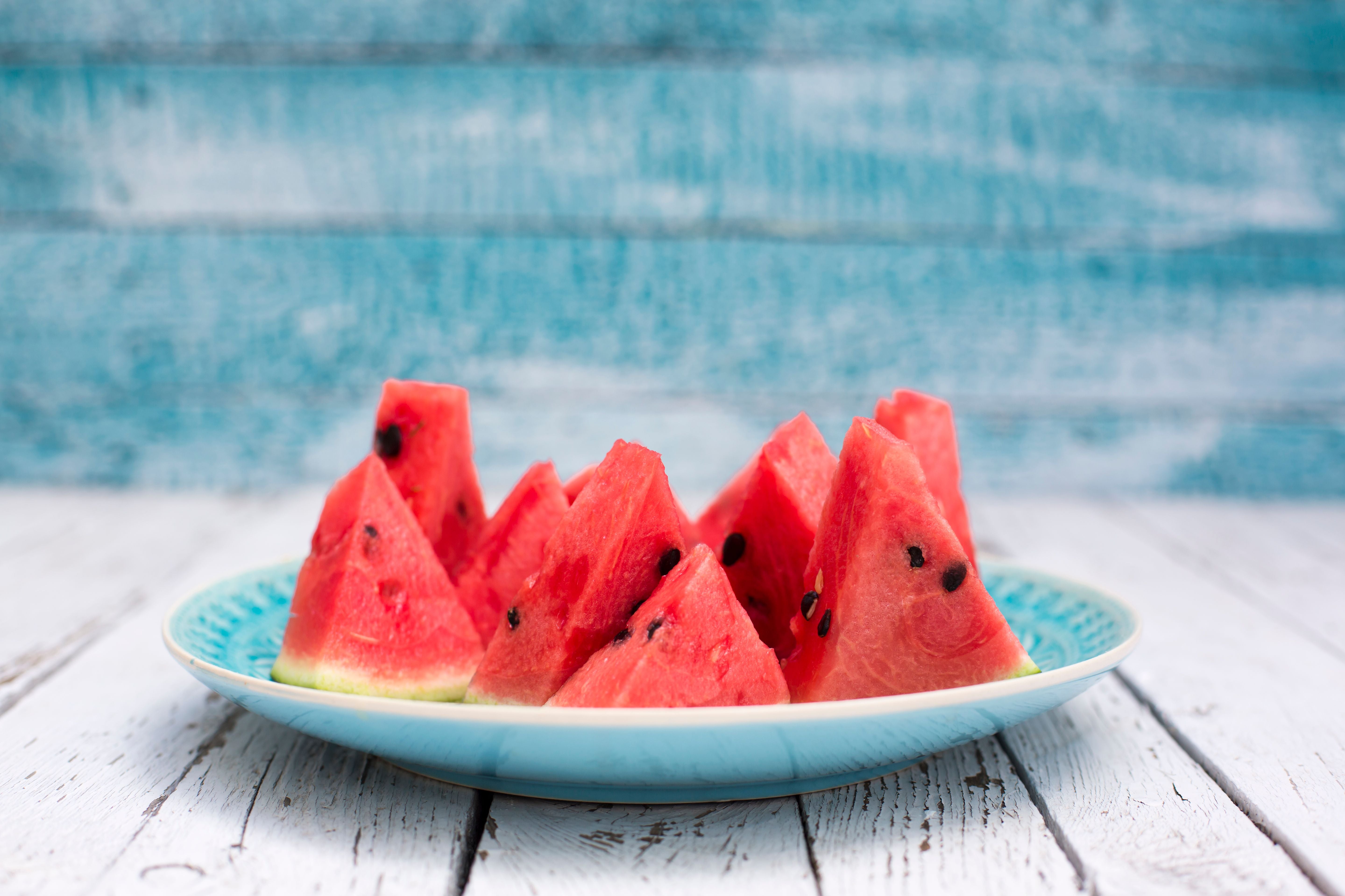 Dreieckige Stücke Wassermelone mit Kernen auf einem blauen Teller.