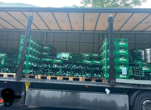Ein Lkw mit offenen Seiten zeigt viele grüne Bierkisten der Marke Gösser auf Paletten.