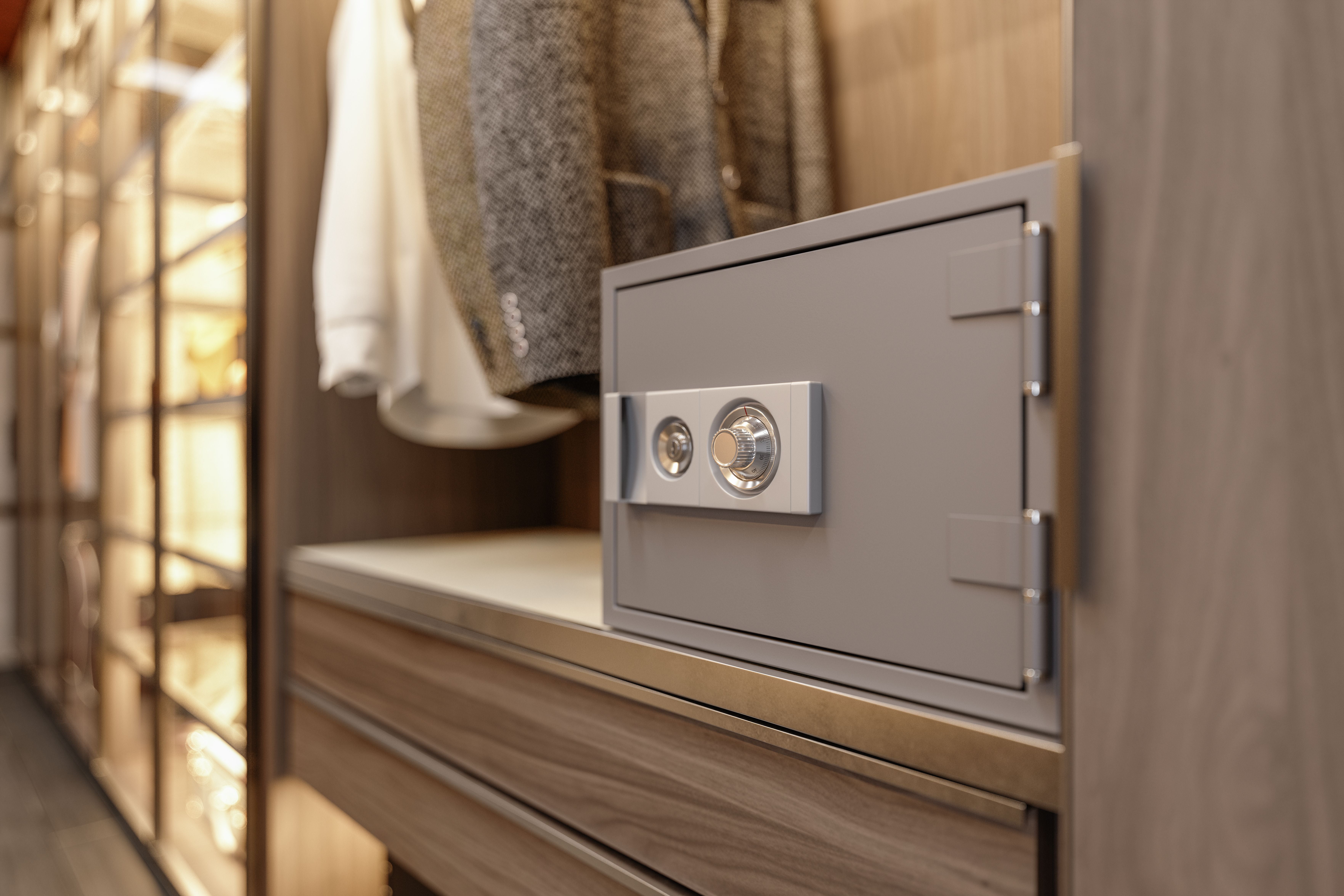 Grauer Safe mit Zahlenschloss in einem modernen Kleiderschrank.