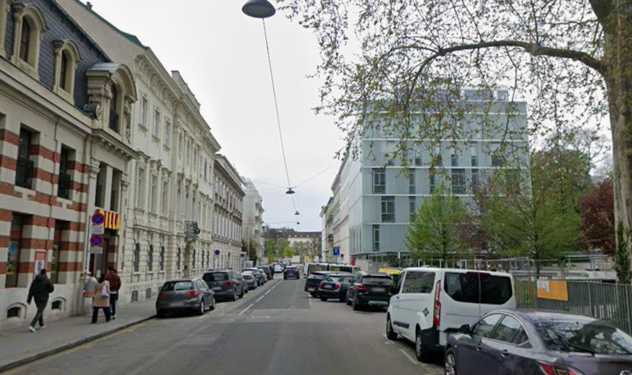 Straßenszene mit geparkten Autos, Passanten und Gebäuden an der Plößlgasse in Wien.
