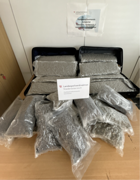 Mehrere Tüten mit Gras liegen auf einem Tisch vor einem Schild der Landespolizeidirektion.
