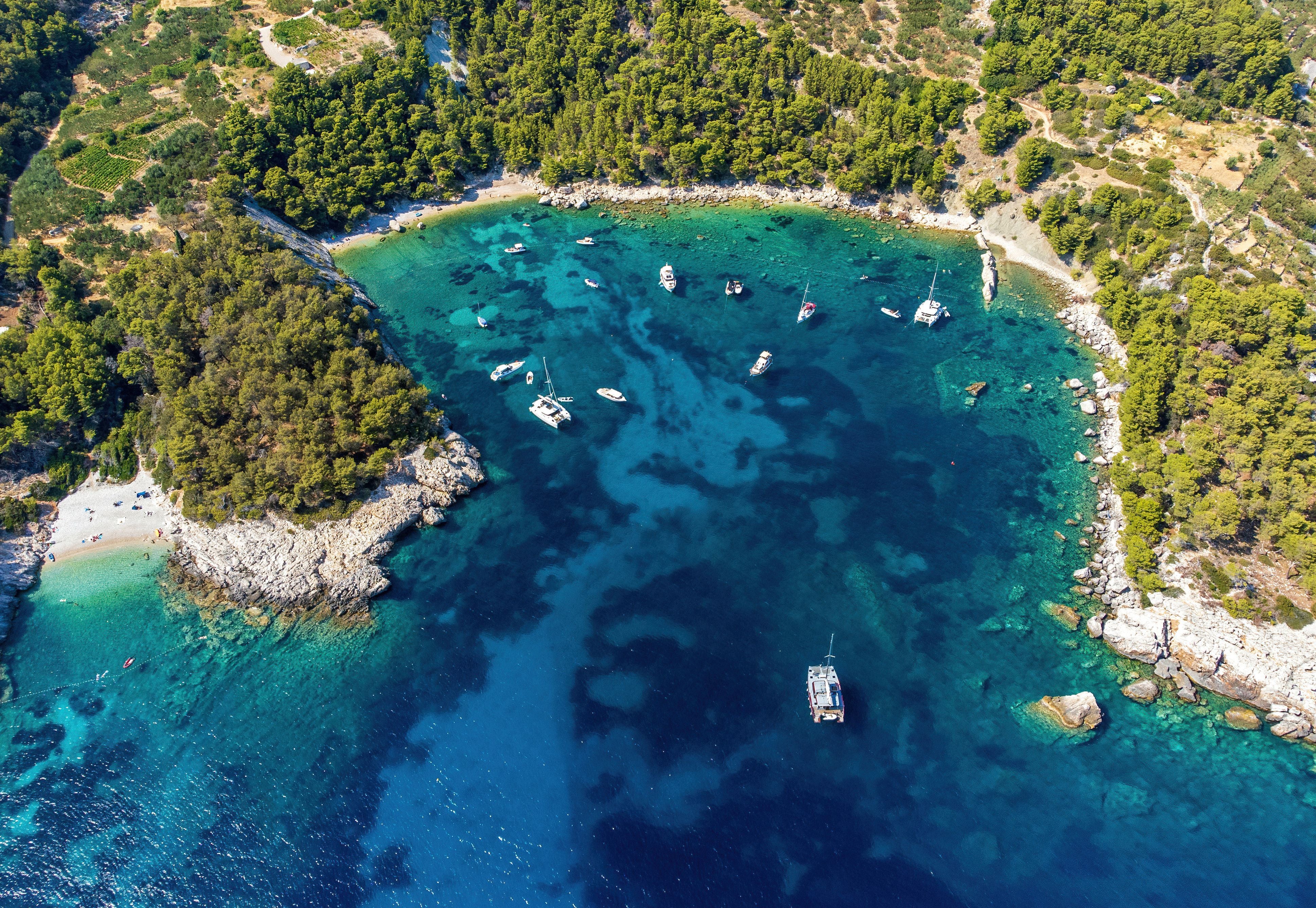 Luftaufnahme von Booten in einer türkisblauen Bucht bei Velo Borce Strand auf Hvar, Kroatien.