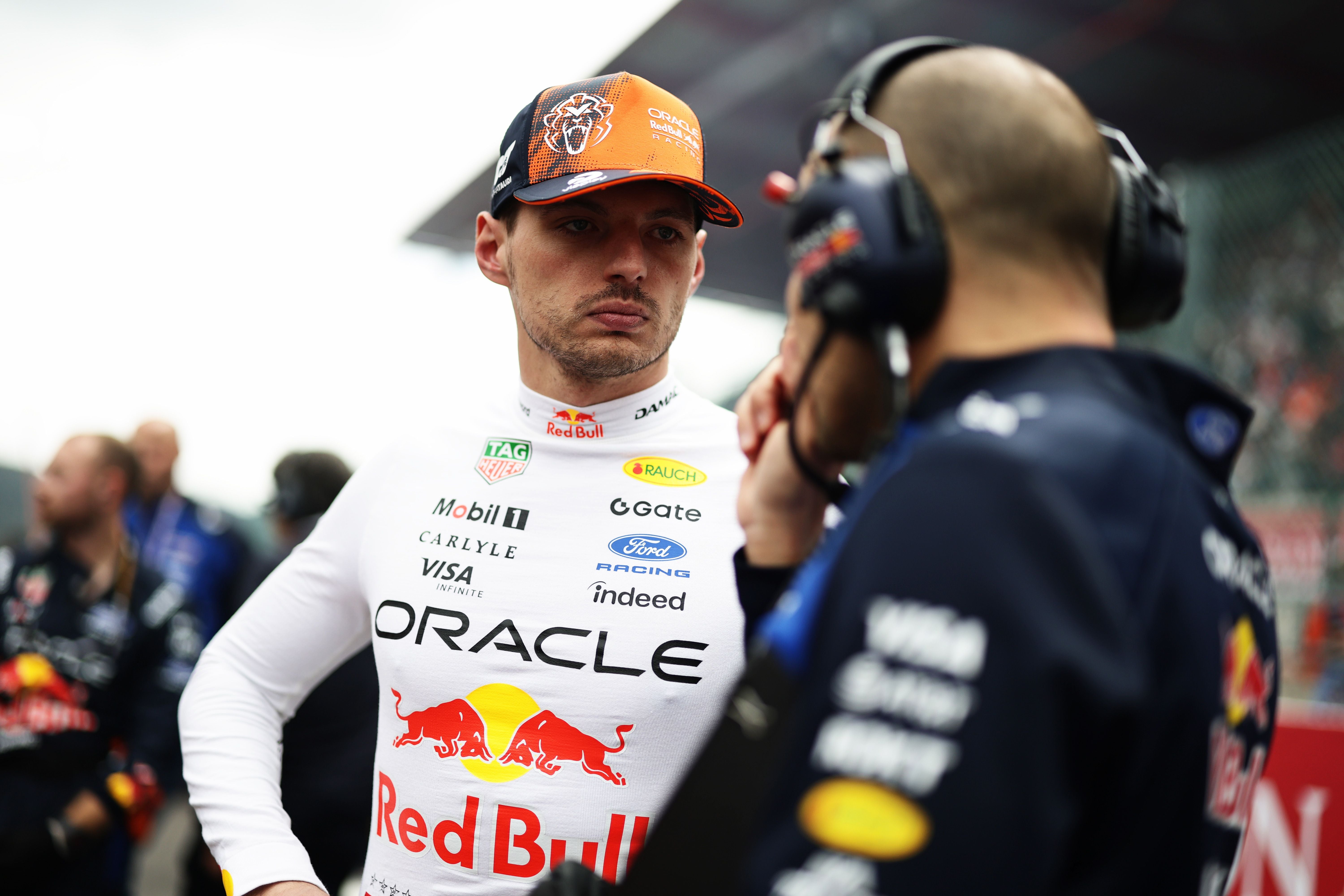 Ein Red-Bull-Fahrer spricht mit einem Ingenieur auf der Startaufstellung einer Rennstrecke.