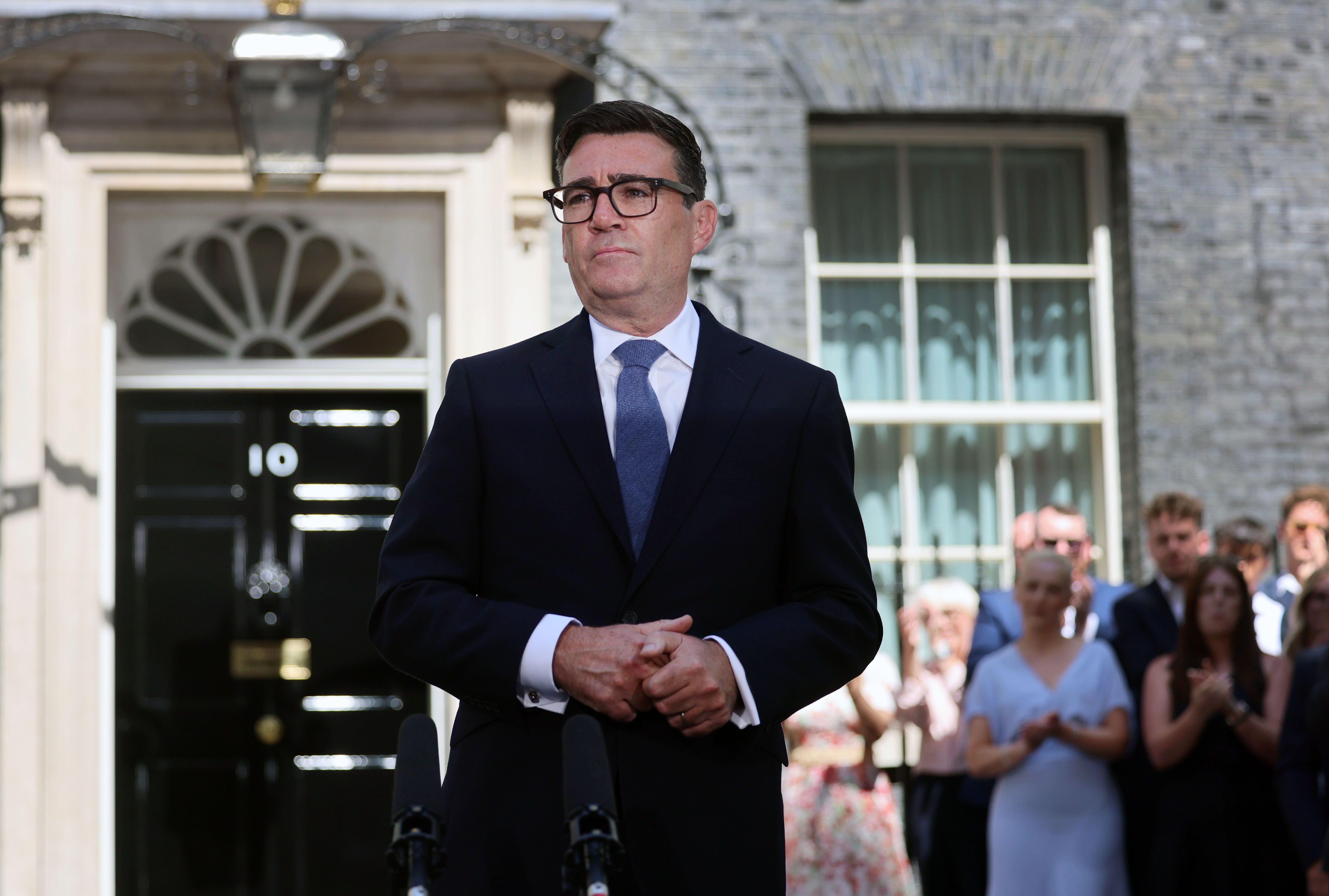 Ein Mann im Anzug spricht vor 10 Downing Street, Menschen stehen applaudierend im Hintergrund.