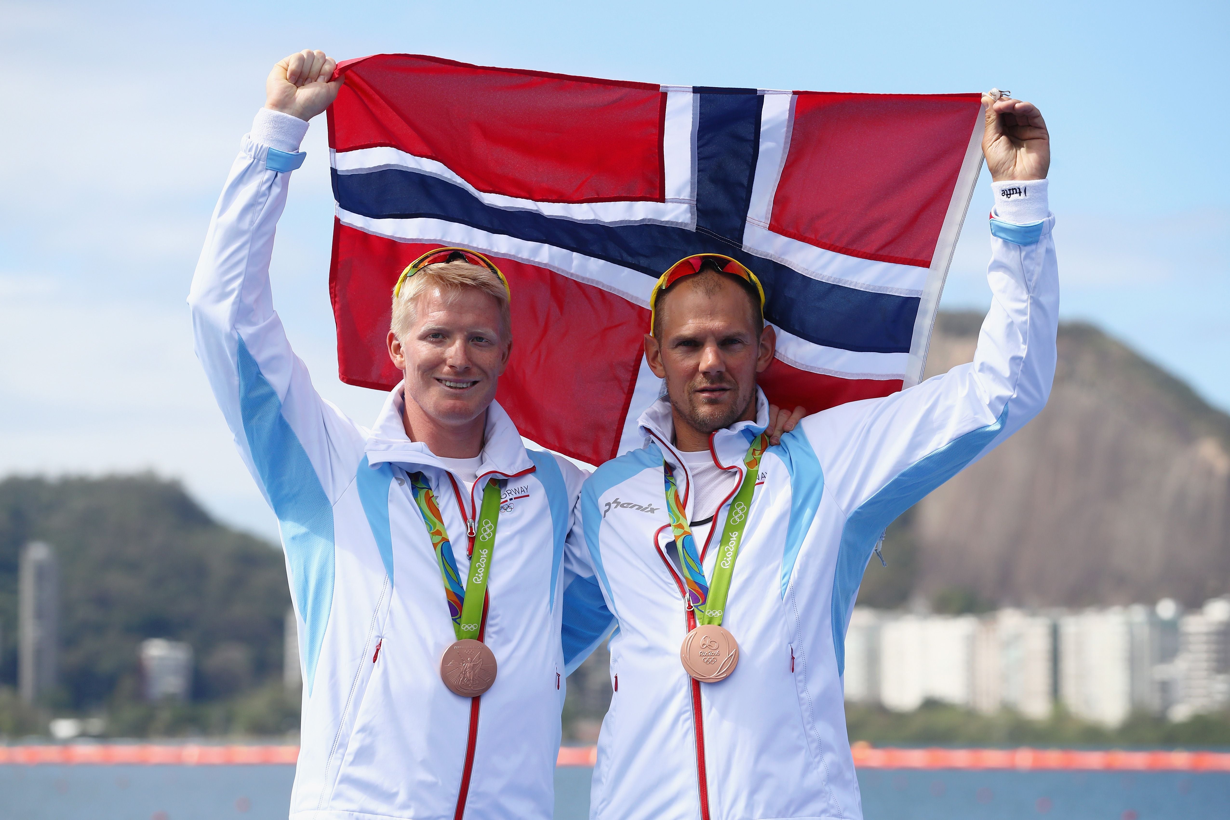 Zwei norwegische Ruderer mit Bronzemedaillen halten eine norwegische Flagge bei den Olympischen Spielen.