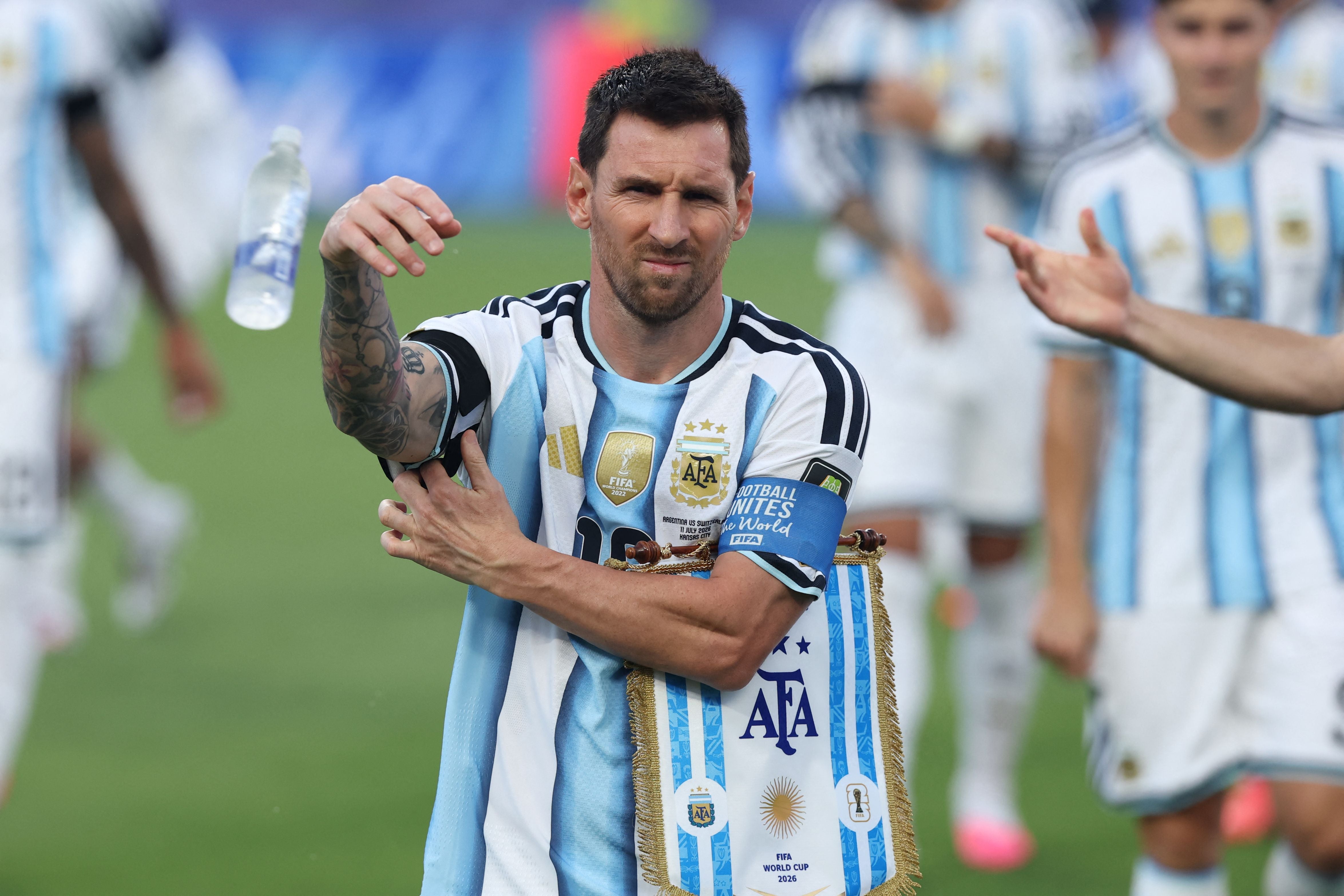 Ein argentinischer Fußballspieler mit Kapitänsbinde steht auf dem Spielfeld und hält eine Fahne.