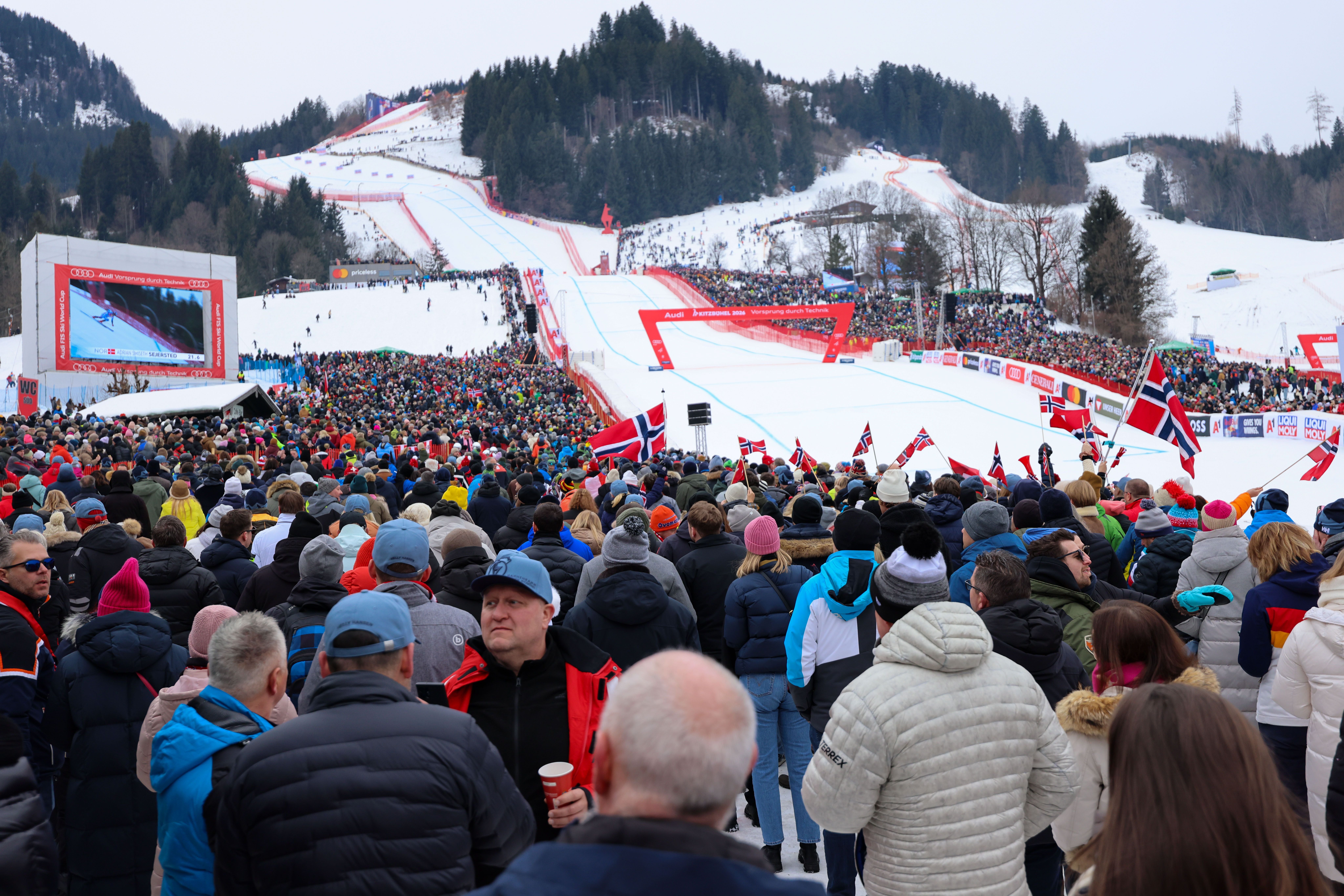 Viele Fans stehen im Zielbereich eines Skirennens in Kitzbühel und halten Fahnen.