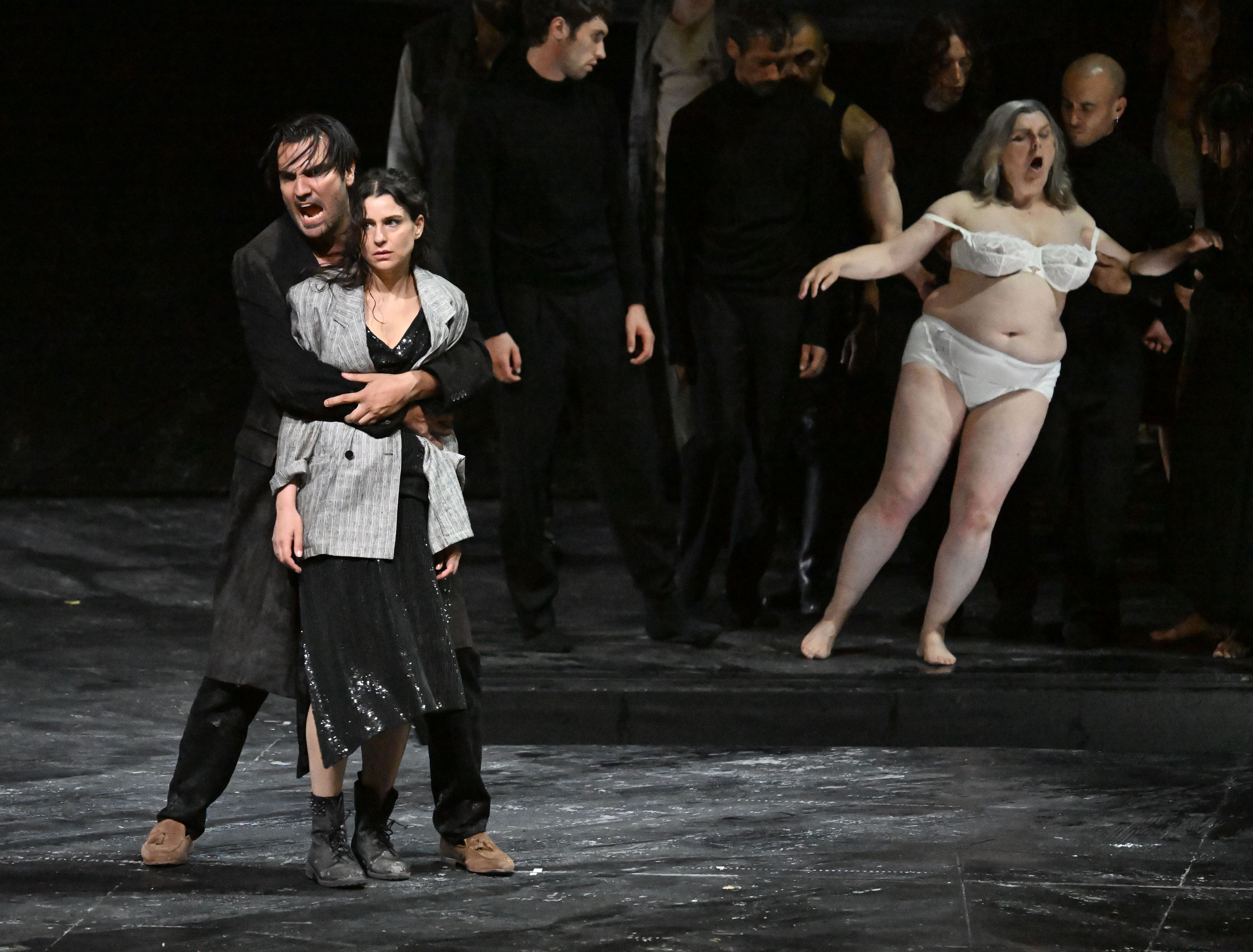 Szenenfoto aus der Oper "Carmen" mit Darstellern auf der Bühne, eine Frau in Unterwäsche rechts.