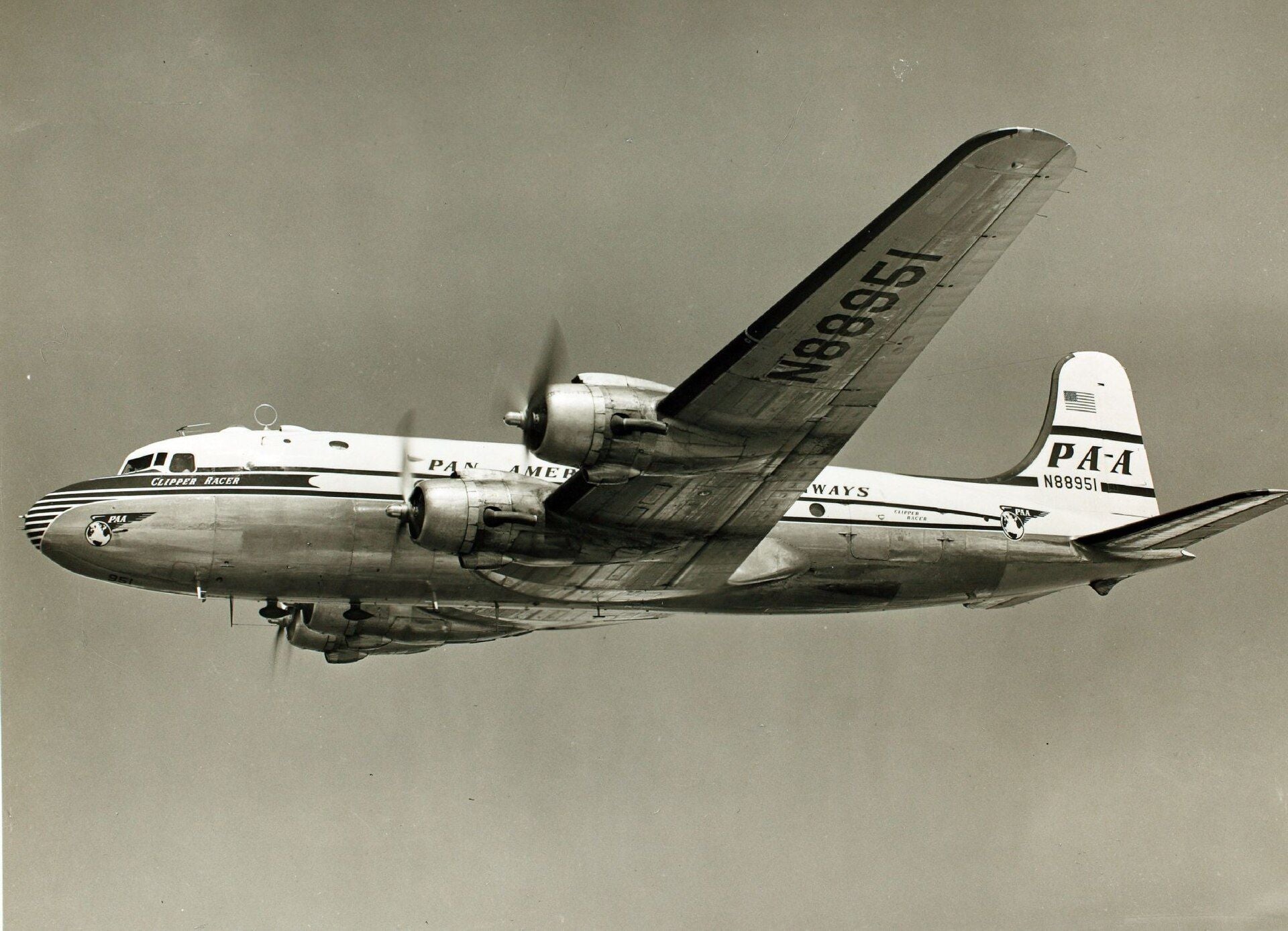 Historisches PanAm-Flugzeug vom Typ Clipper Racer im Flug vor klarem Himmel.
