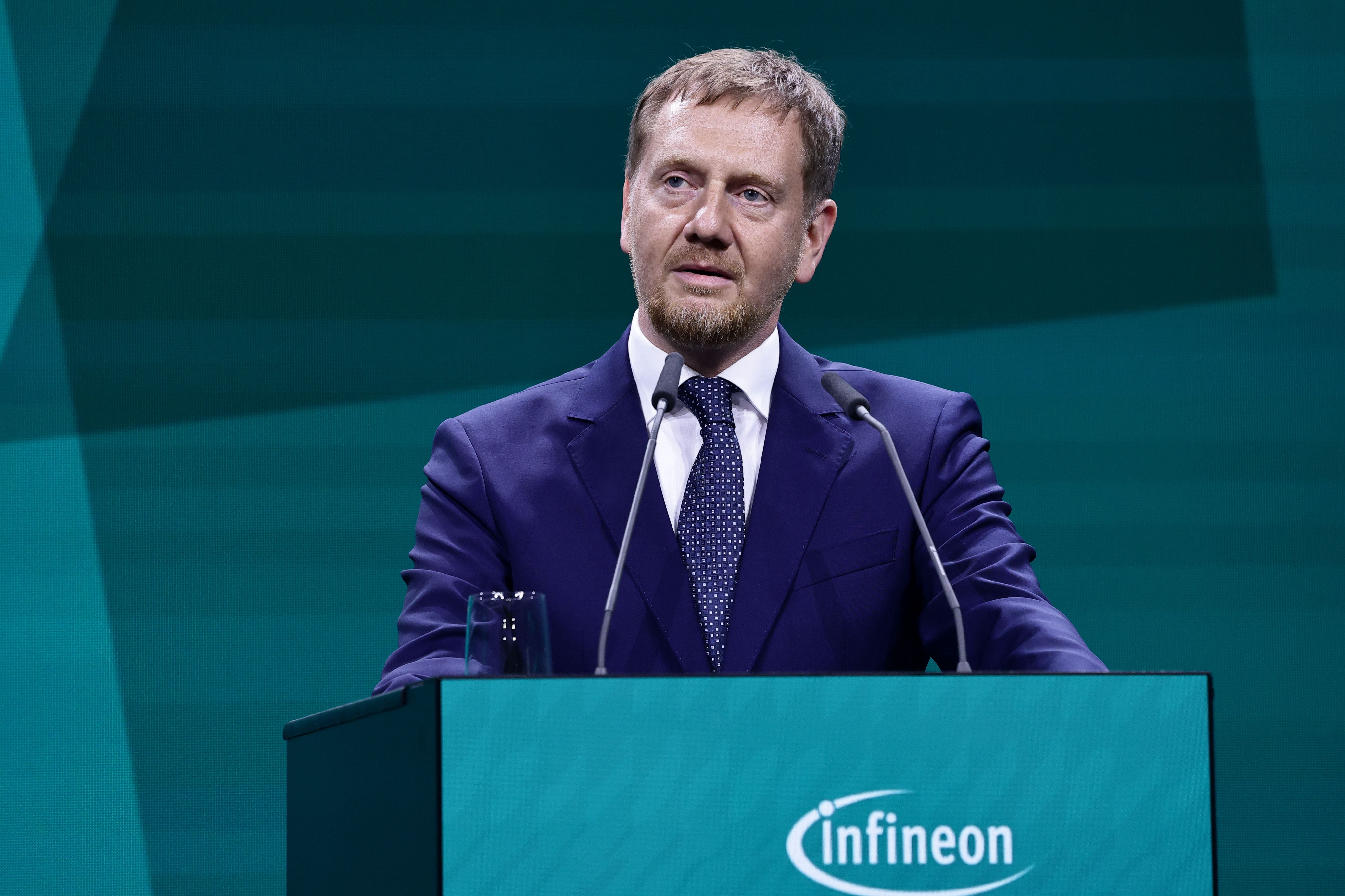 Ein Mann im Anzug spricht am Rednerpult bei einer Infineon-Veranstaltung in Dresden.