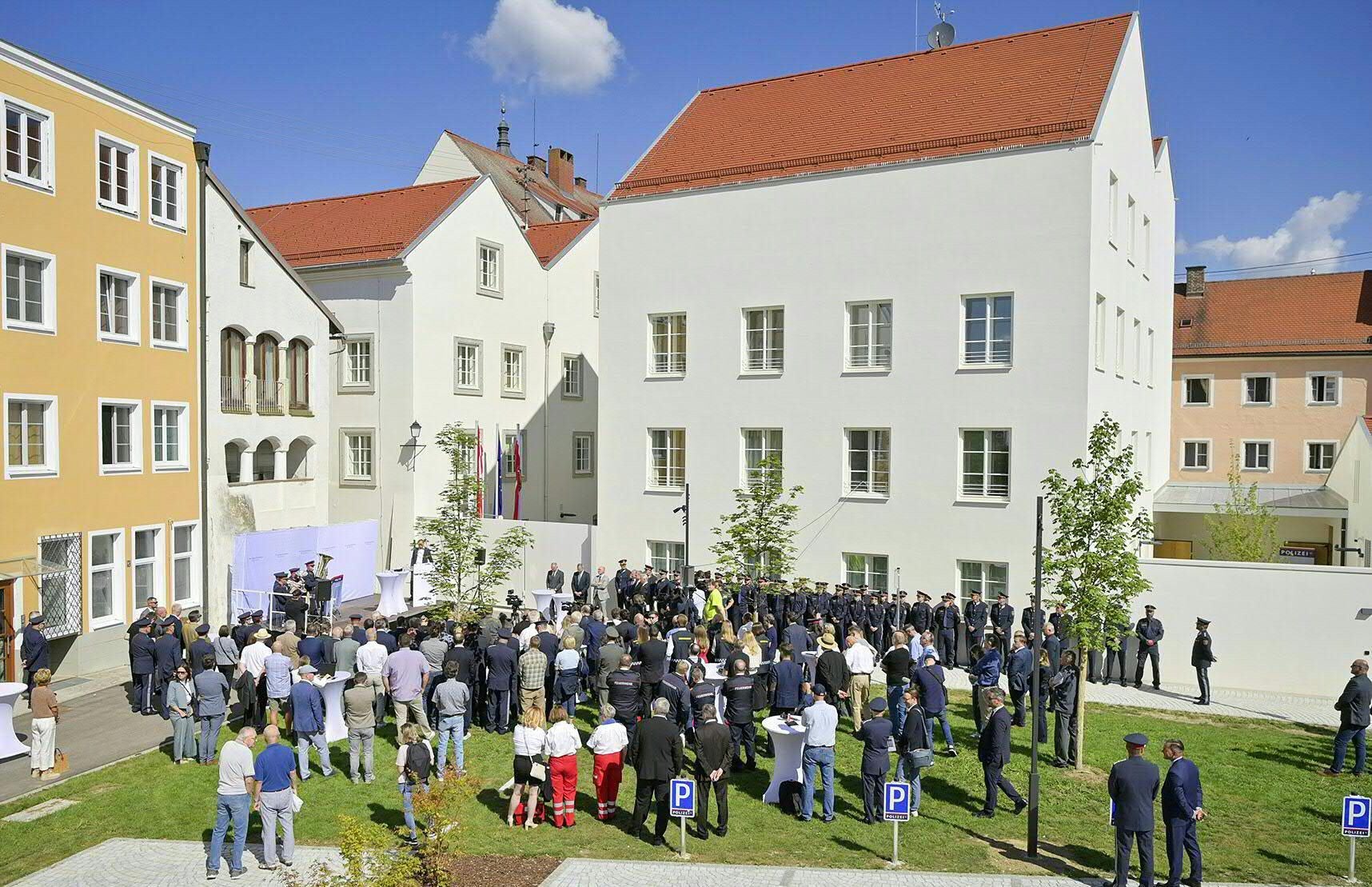 Zahlreiche Menschen versammeln sich zur Eröffnung des Polizeizentrums vor einem renovierten Gebäude.