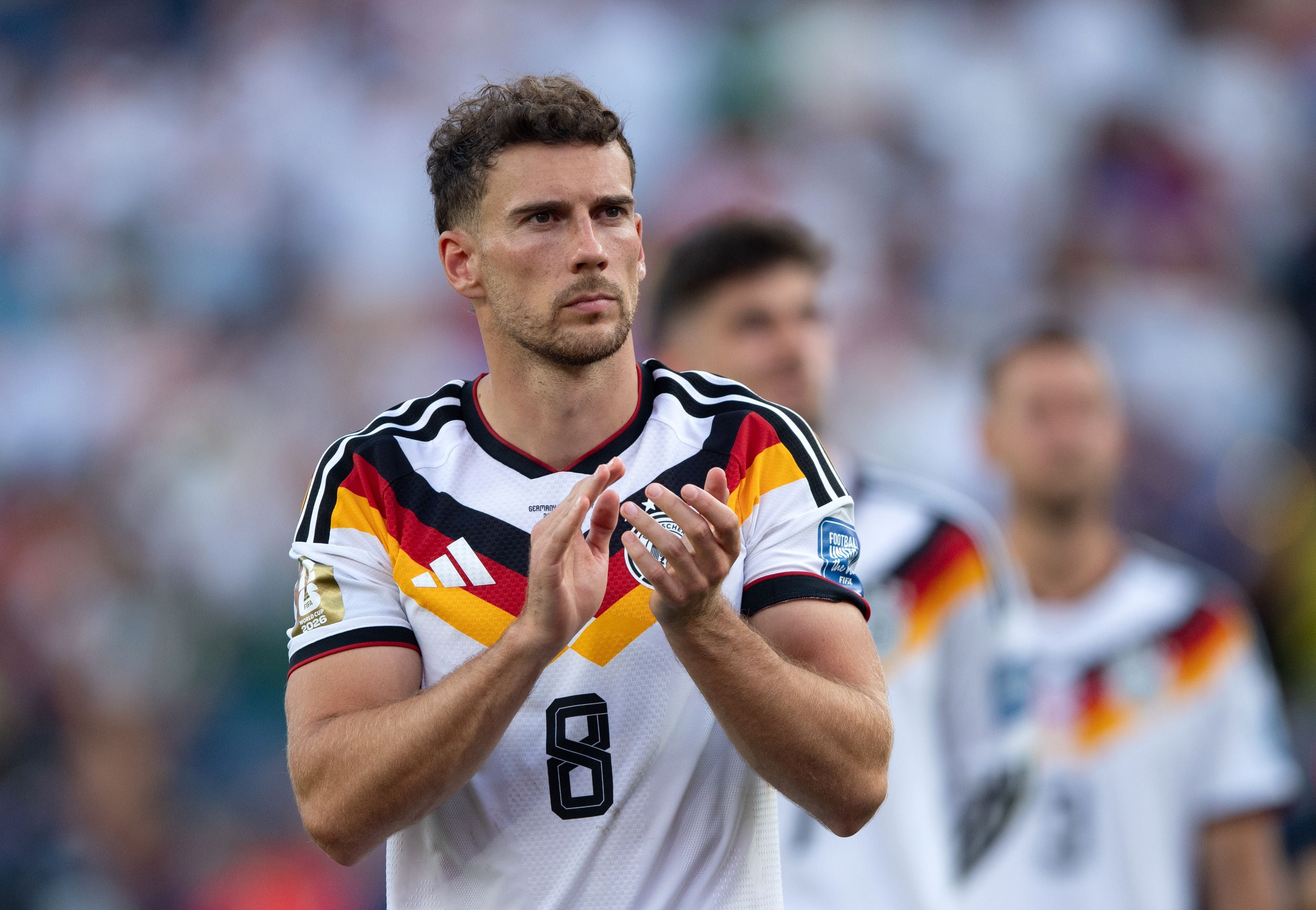 Ein deutscher Fußballspieler im weißen Trikot klatscht nach einem Spiel auf dem Spielfeld.