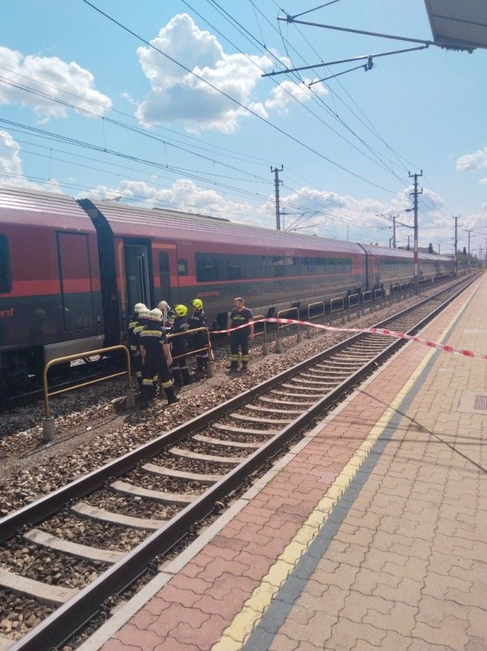 Feuerwehrleute evakuieren Menschen aus einem stehenden Railjet-Zug am Bahnsteig.
