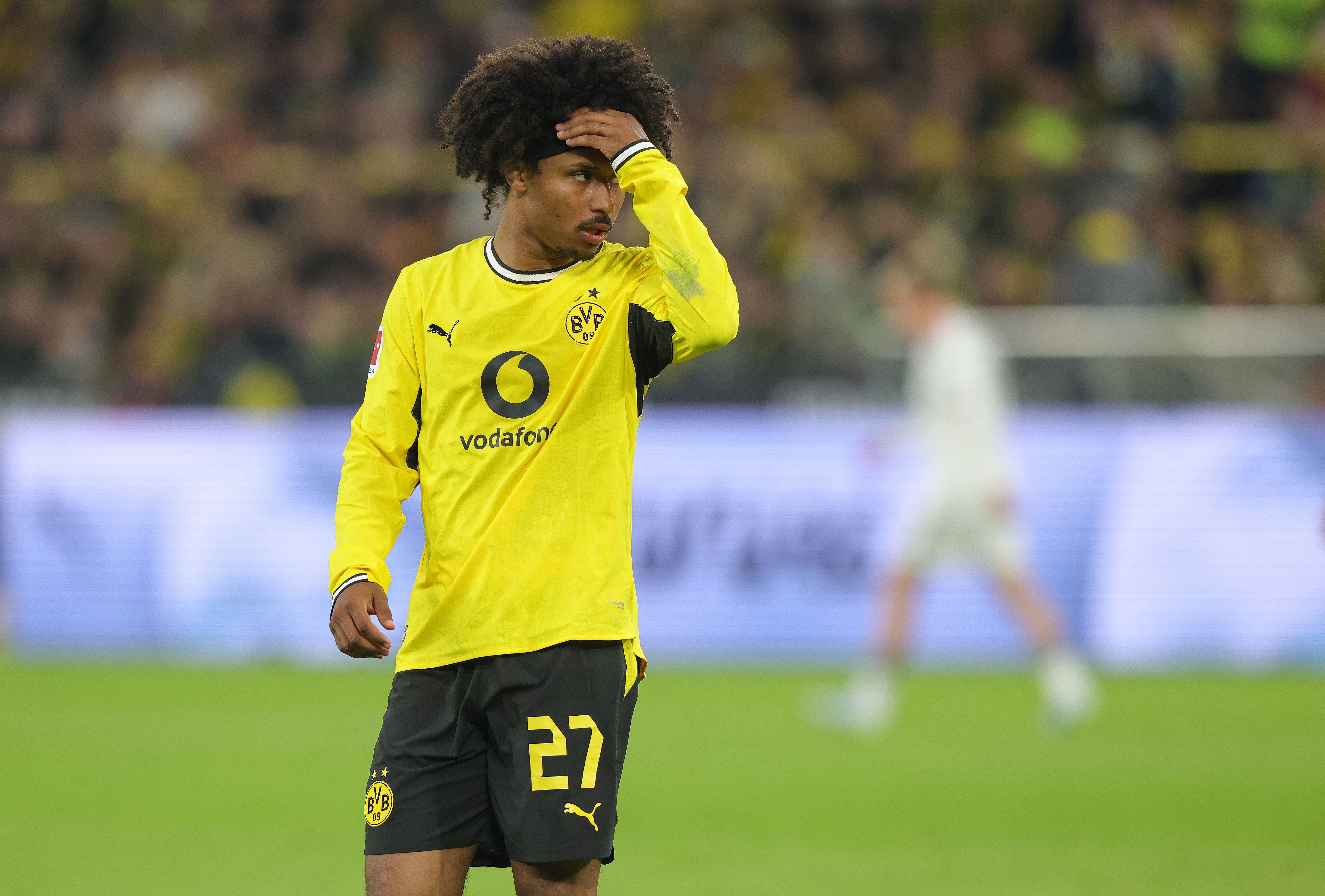 Ein Borussia Dortmund Spieler im gelben Trikot hält sich nachdenklich die Stirn auf dem Spielfeld.