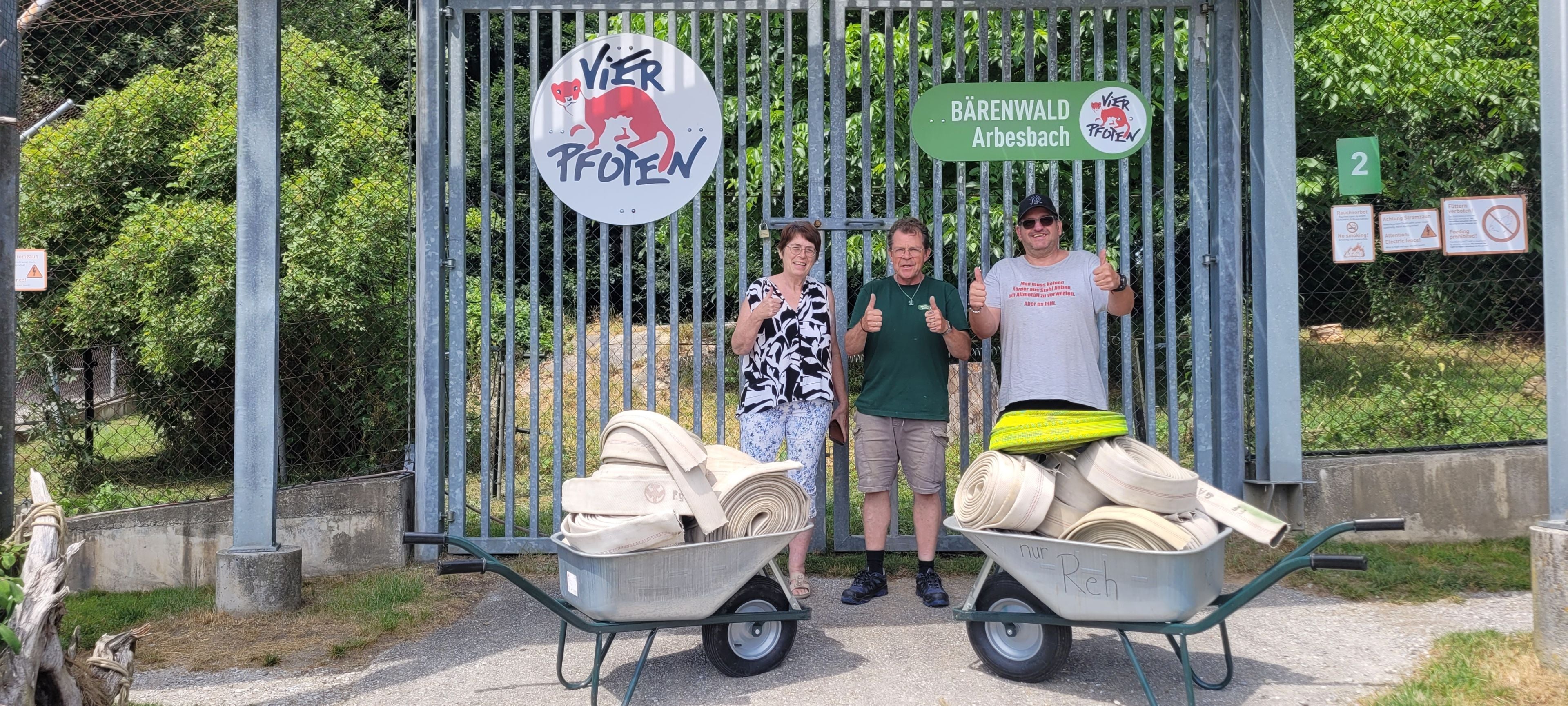 Drei Menschen mit Schubkarren voller alter Feuerwehrschläuche vor dem Bärenwald Arbesbach.