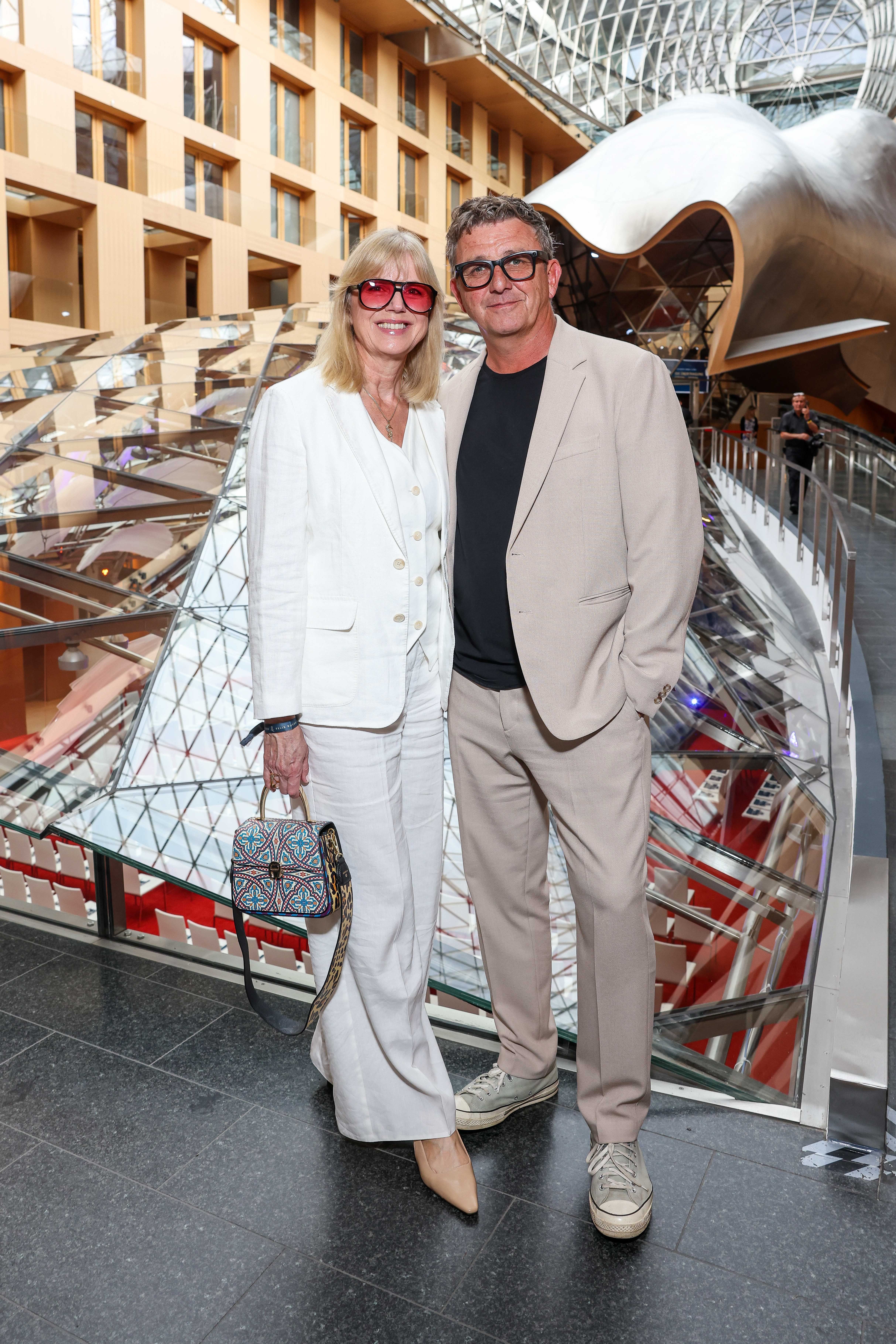 Ein Mann und eine Frau posieren lächelnd in moderner, heller Architektur.