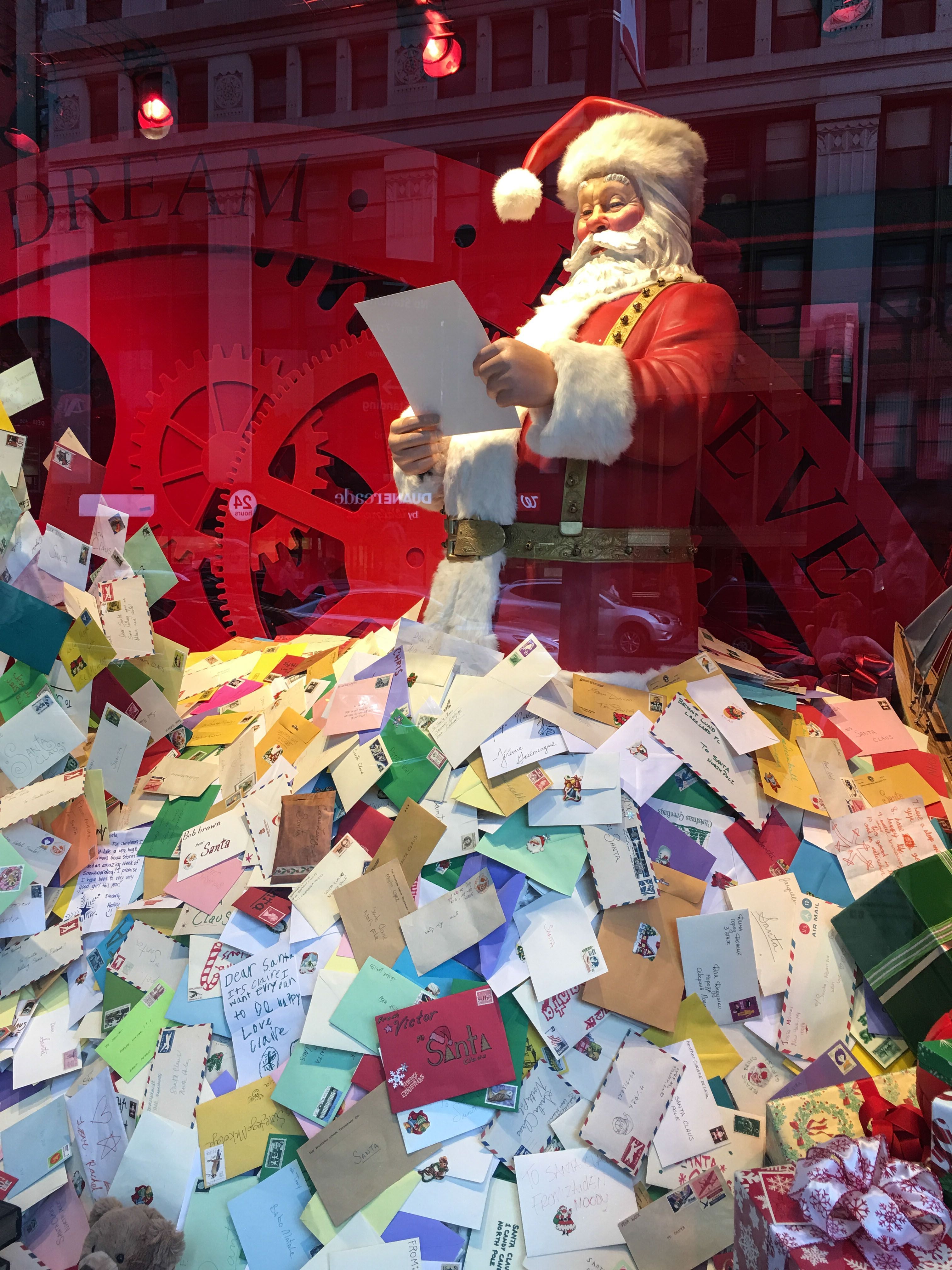 Schaufenster mit Weihnachtsmann-Figur, umgeben von vielen bunten Briefen und Wunschzetteln an Santa.