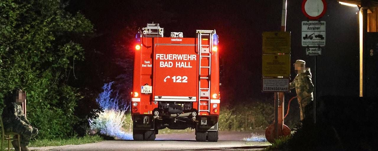 Ein Feuerwehrauto der Feuerwehr Bad Hall steht nachts auf einer Straße, daneben Einsatzkräfte.