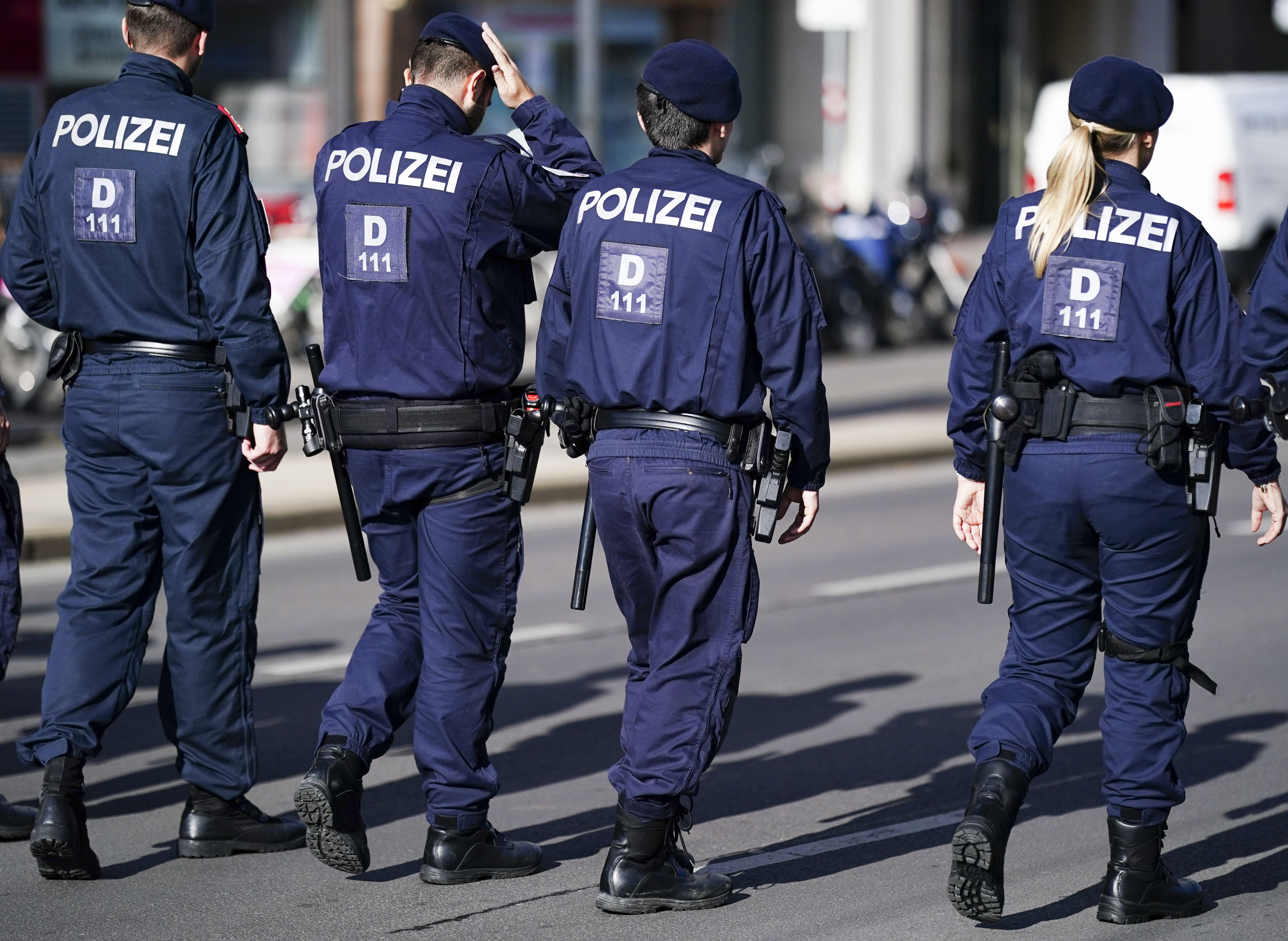 Vier Polizisten in Uniform gehen gemeinsam auf einer Straße in Wien.