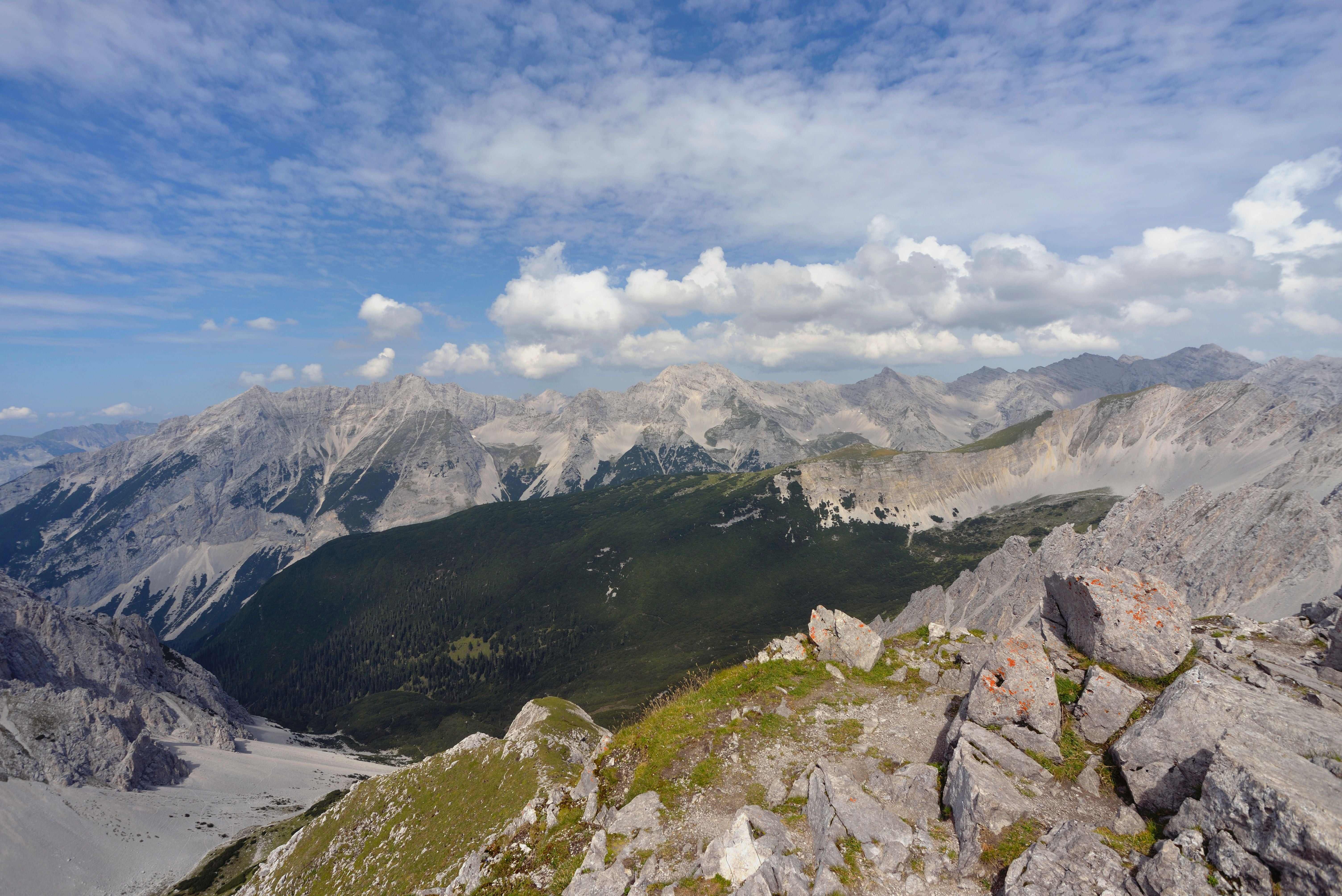 Panorama der Nordkette mit Felsen im Vordergrund und bewaldeten Hängen unterhalb der Gipfel.