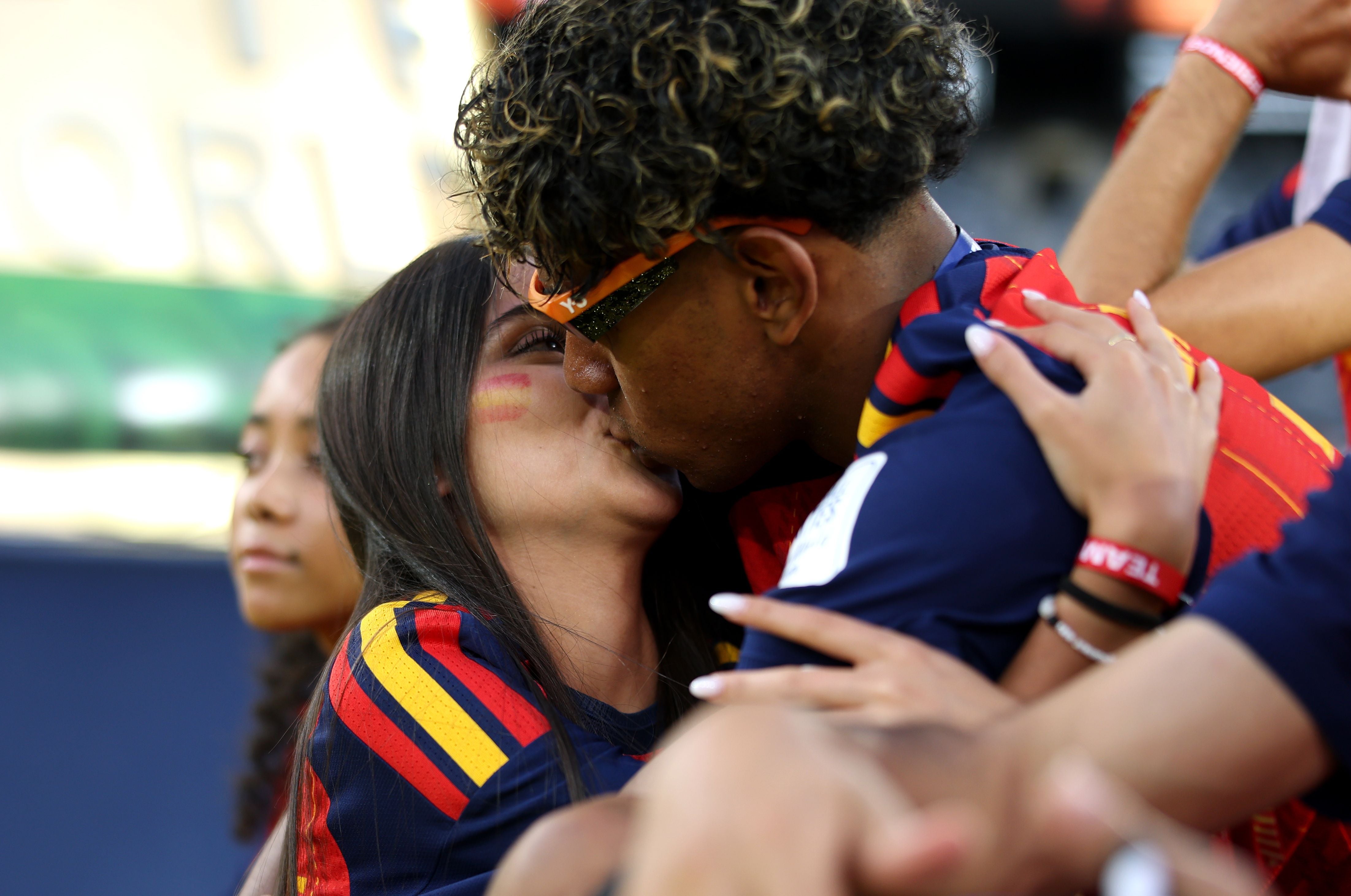 Ein Paar in Spanien-Trikots küsst sich jubelnd im Stadion nach einem Fußballspiel.