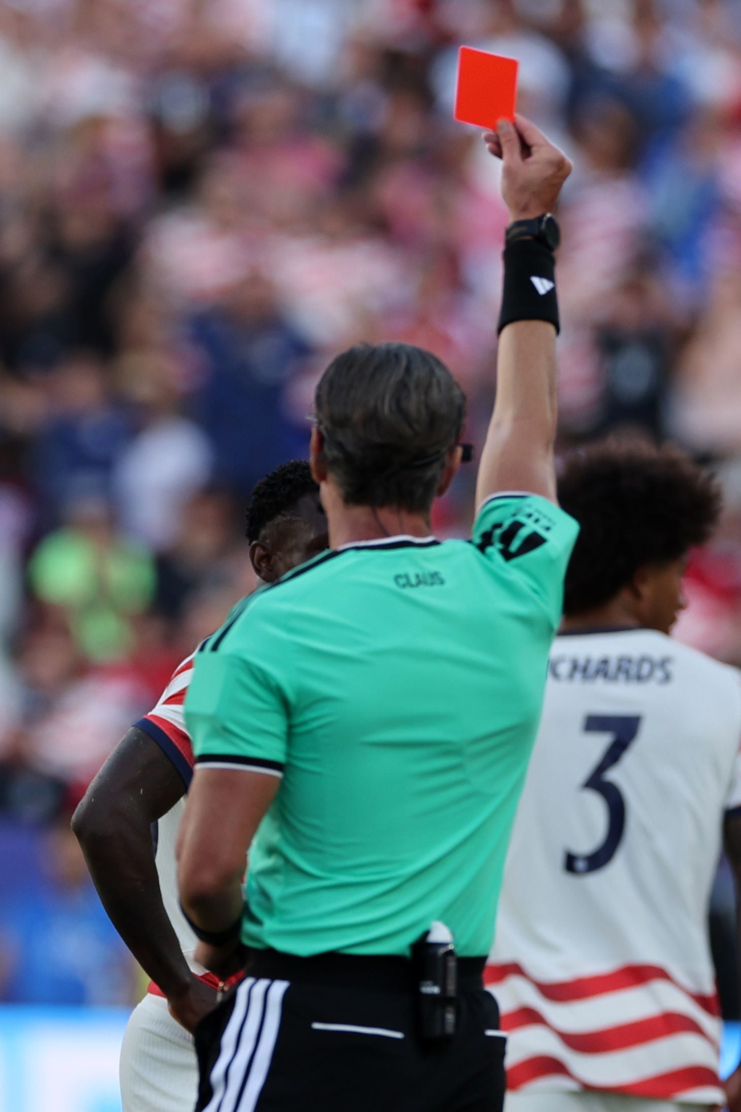 Ein Schiedsrichter zeigt einem US-Spieler beim Fußballspiel eine rote Karte.