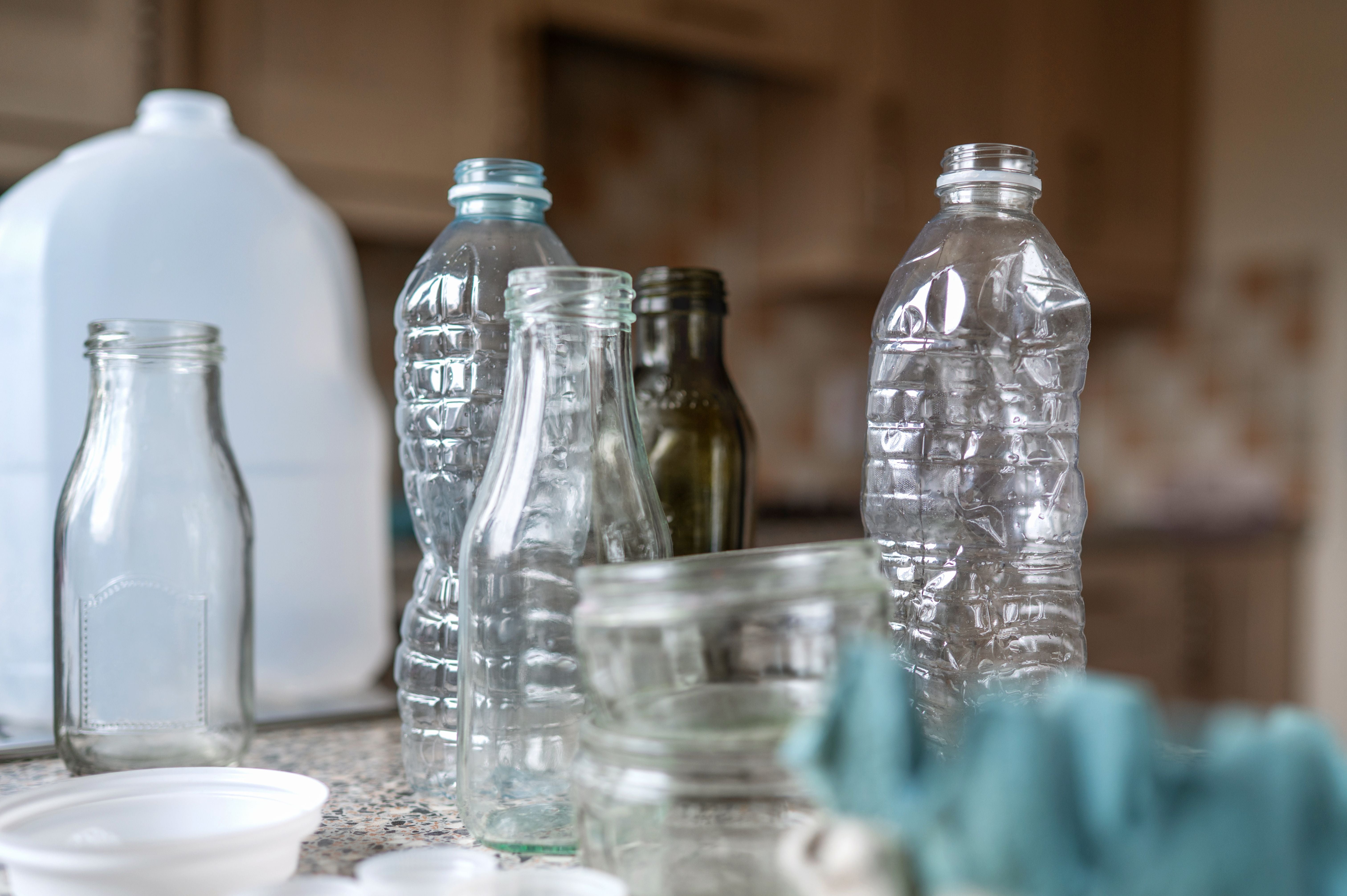 Leere Plastik- und Glasflaschen stehen auf einer Küchenarbeitsplatte zum Recycling bereit.