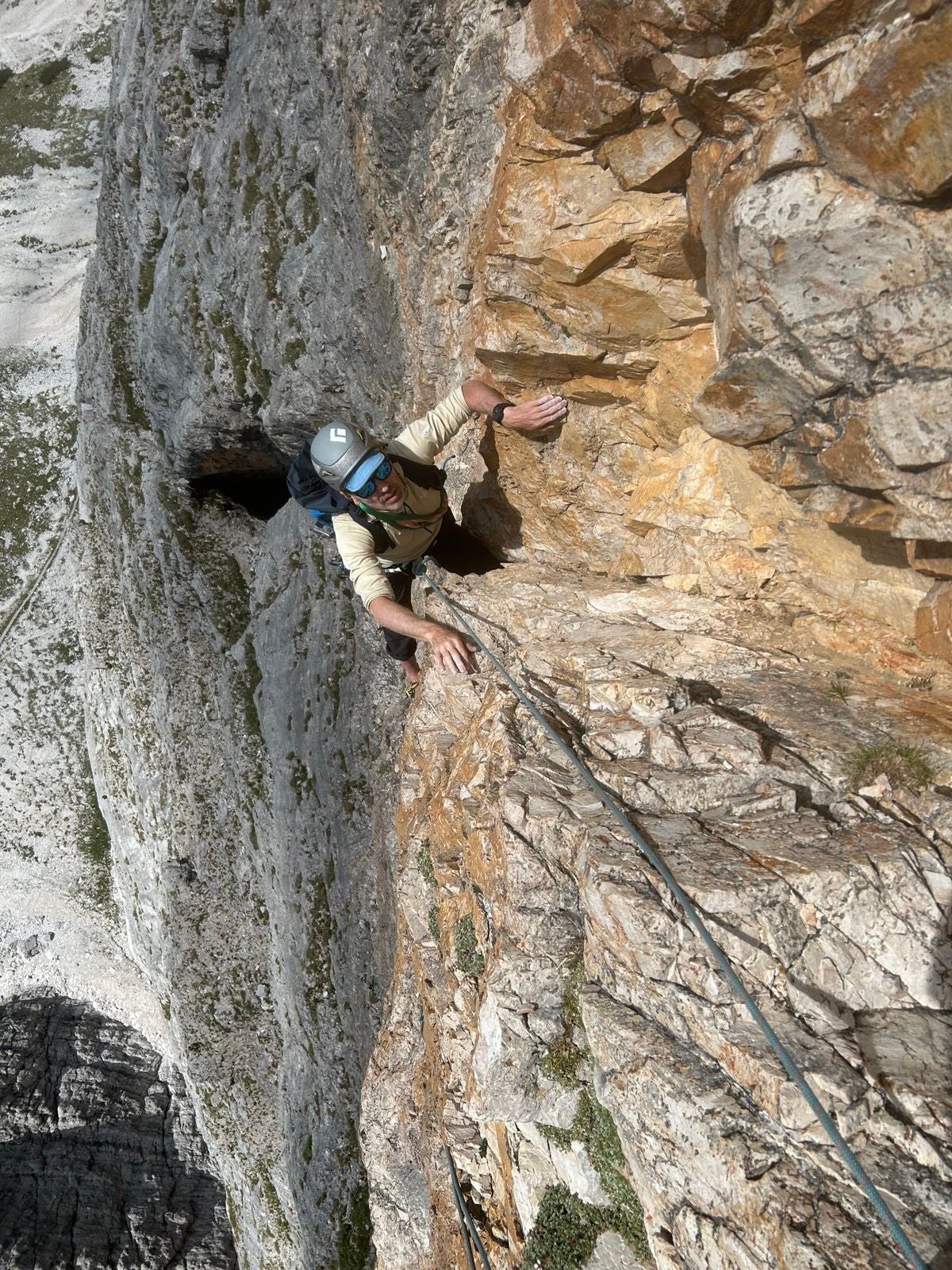 Eine Person klettert an einer steilen Felswand mit Kletterausrüstung nach oben.