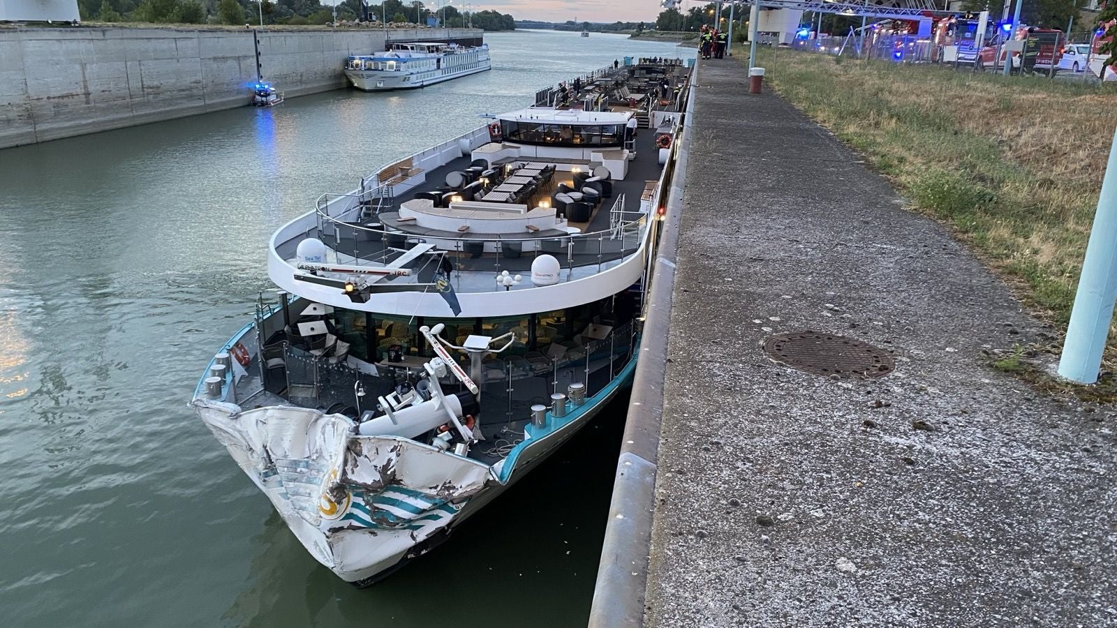 Ein Flusskreuzfahrtschiff mit stark beschädigtem Bug liegt an einer Kaimauer in einer Schleuse.