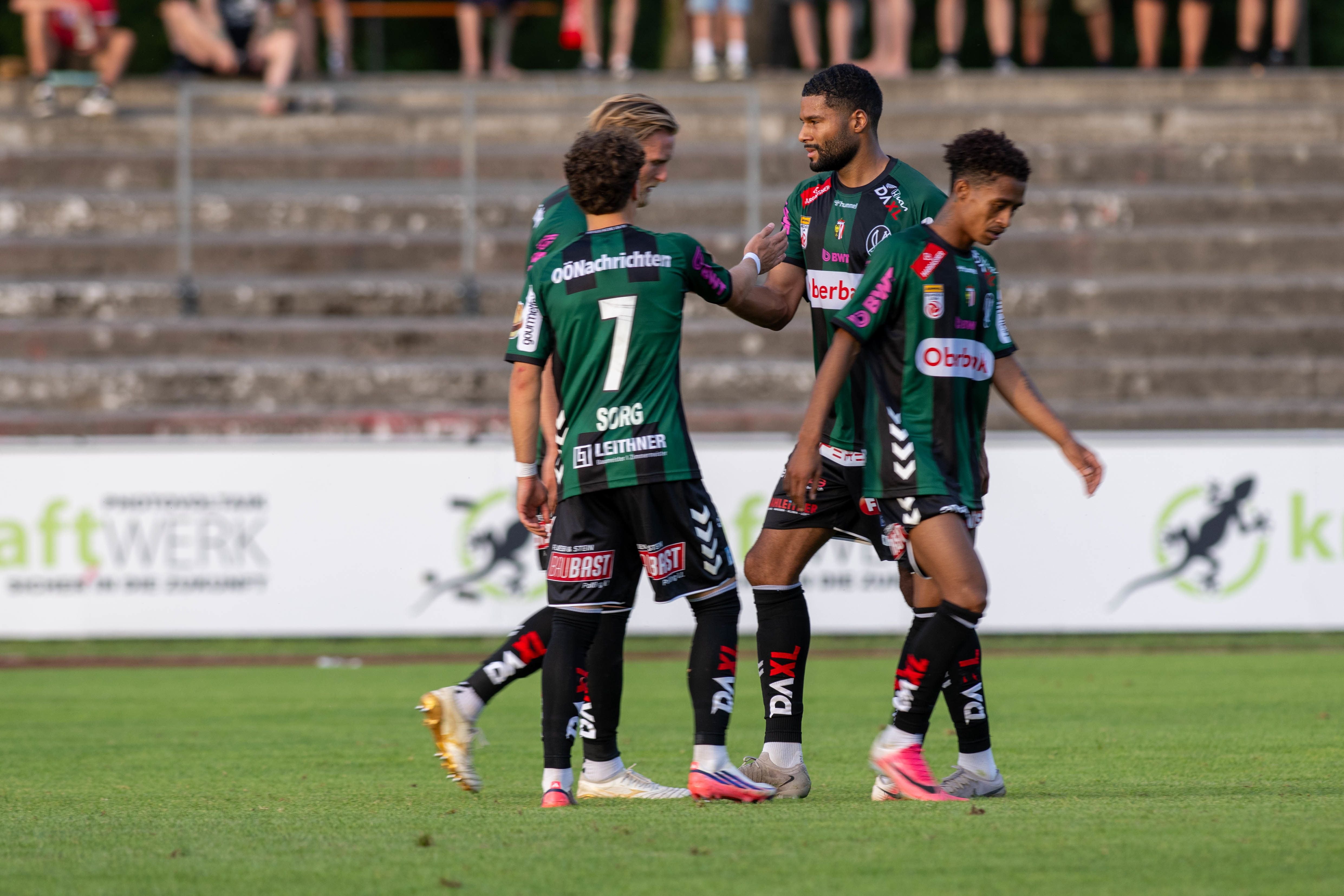Drei Fußballspieler von SV Ried jubeln gemeinsam auf dem Spielfeld.